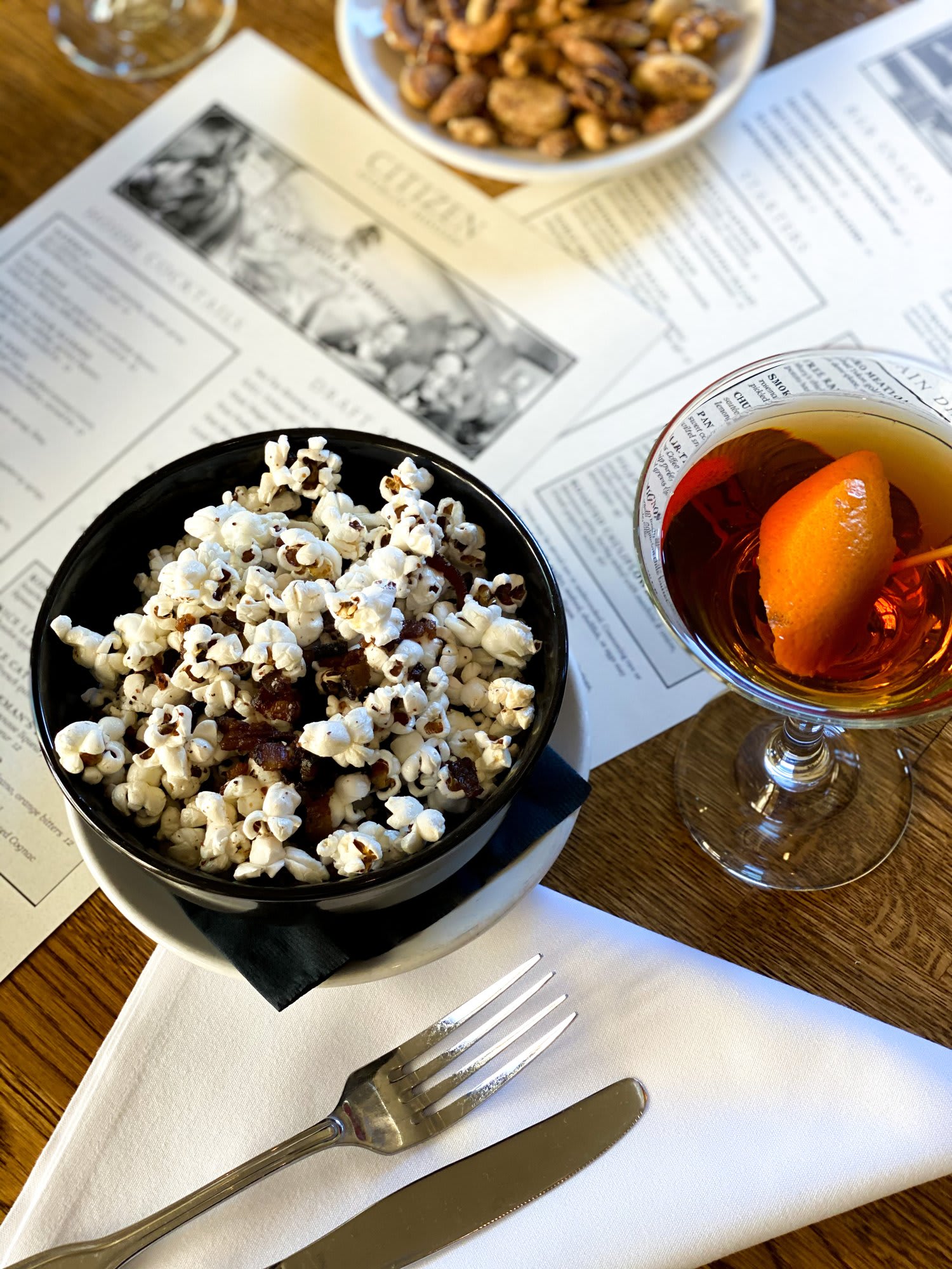 Bowl of gourmet popcorn and a cocktail on a restaurant table.