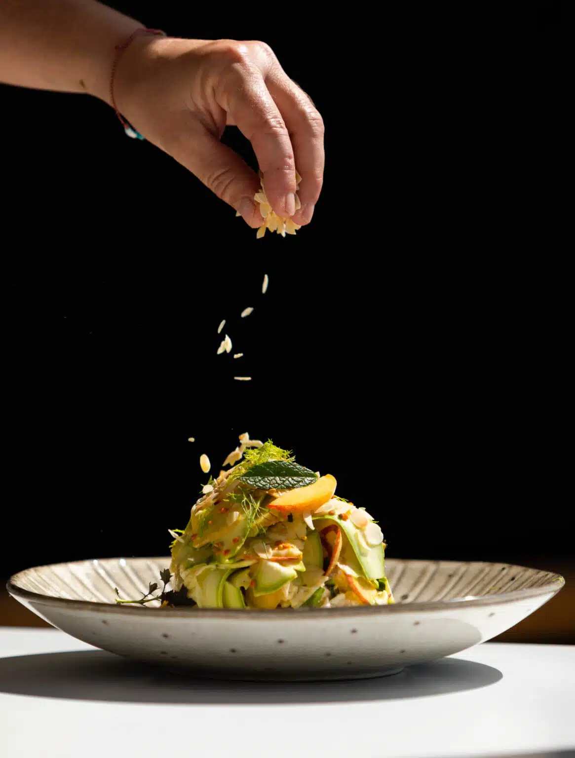A hand sprinkling garnish on a fresh salad in Corfu.