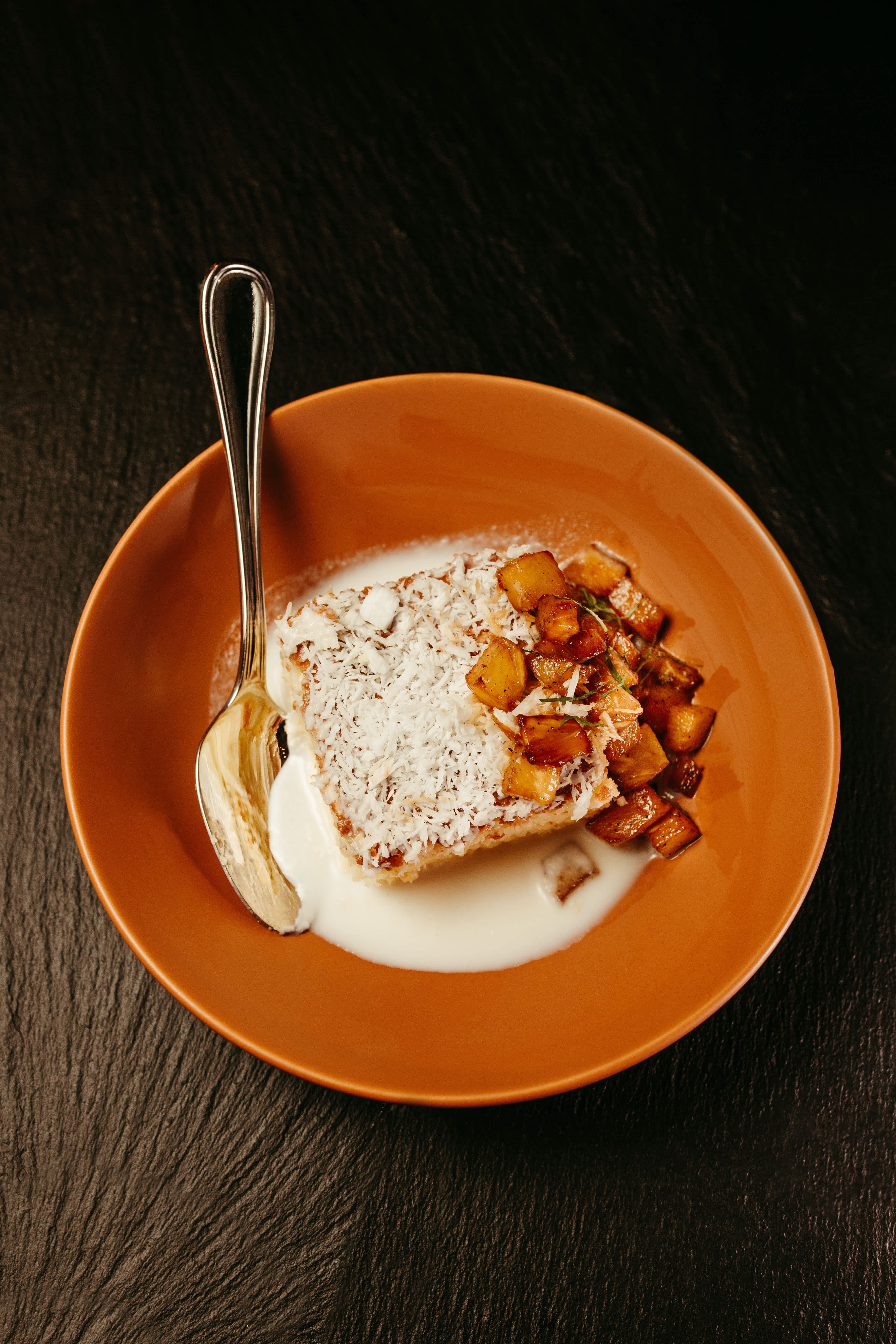 Provence-style dessert with caramelized fruits and a coconut topping served in an orange bowl.