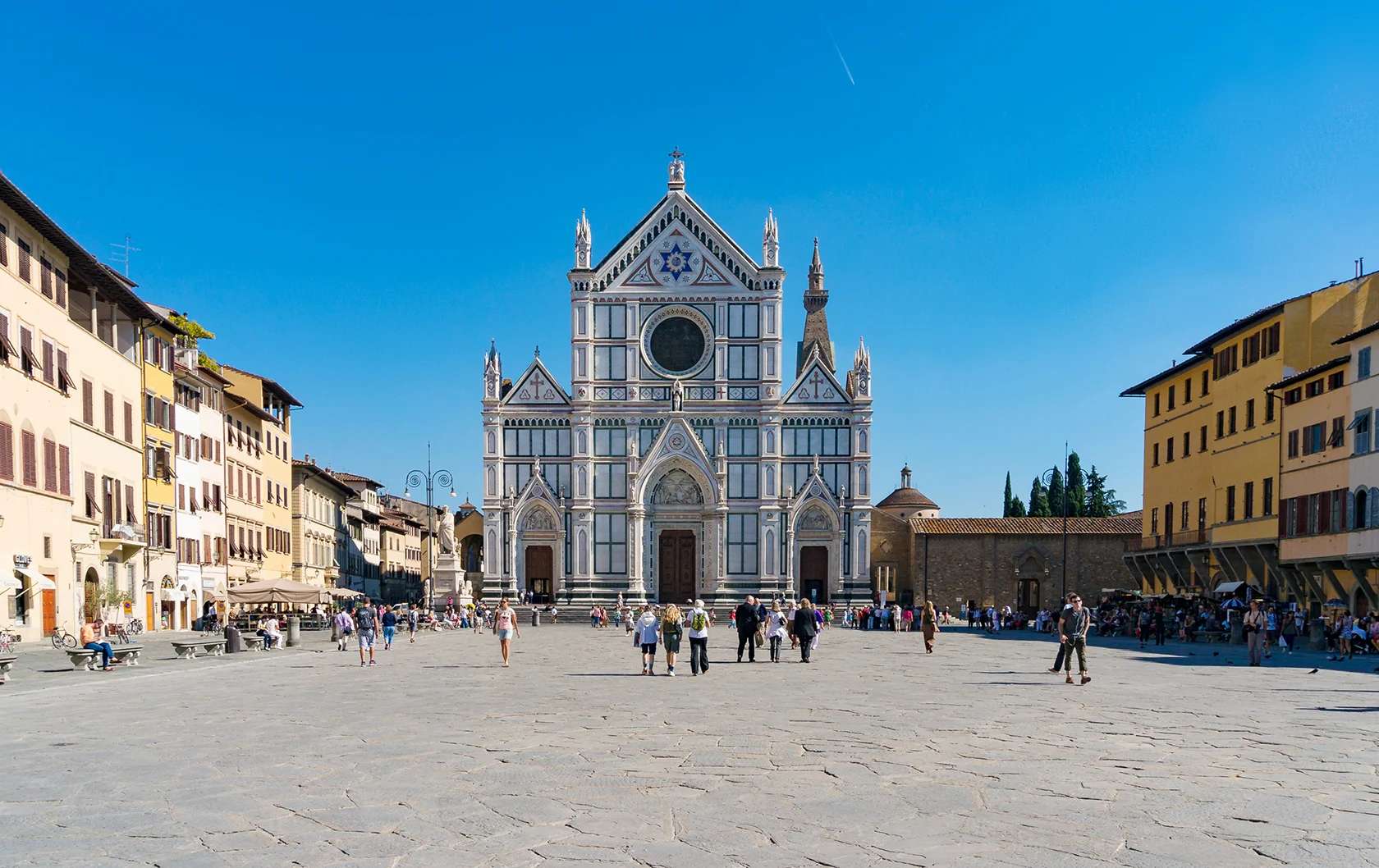 Facade of Santa Maria Novella with people walking in the square