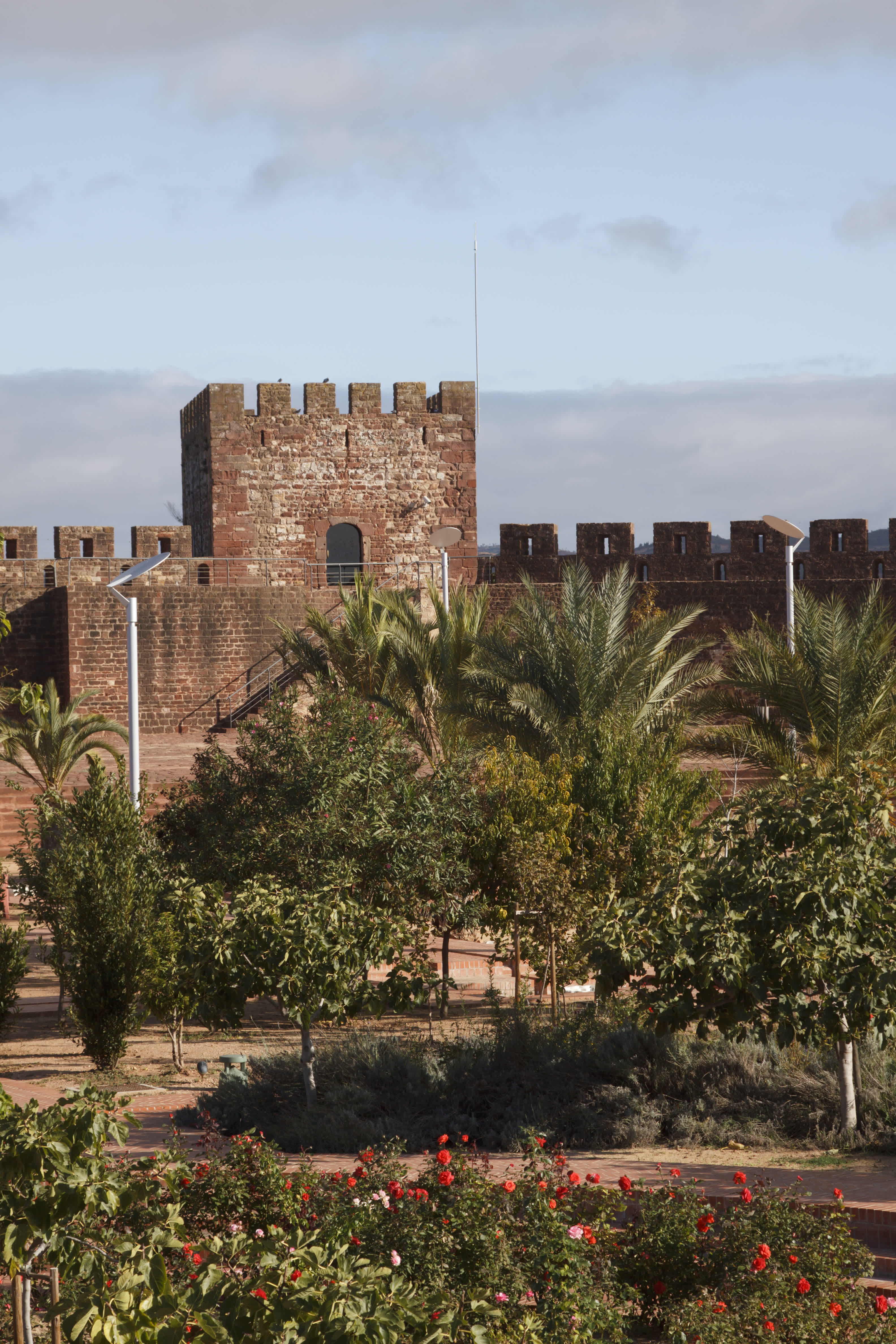 Historic castle with crenelated walls surrounded by palm trees in Algarve, Portugal.