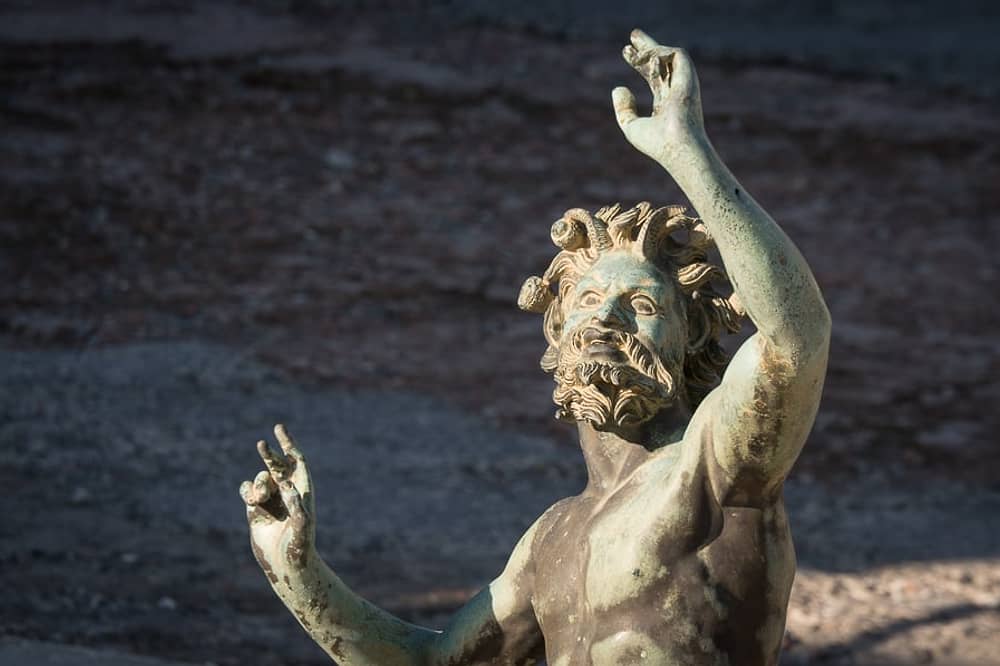 Bronze statue of a mythological figure with a beard and raised arms, possibly representing a god or ancient deity.