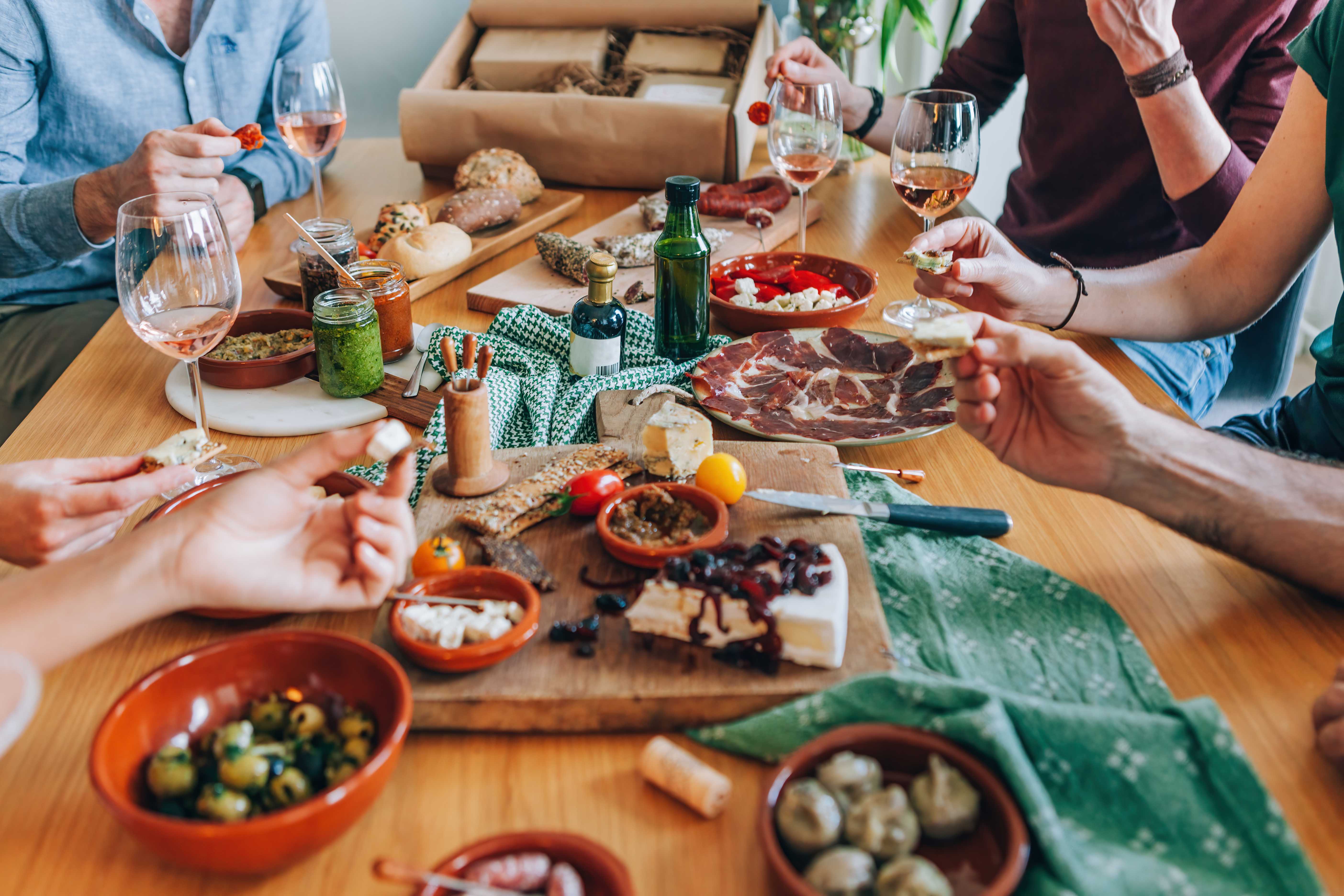 Group of people enjoying a spread of Spanish tapas and wine at a dining table