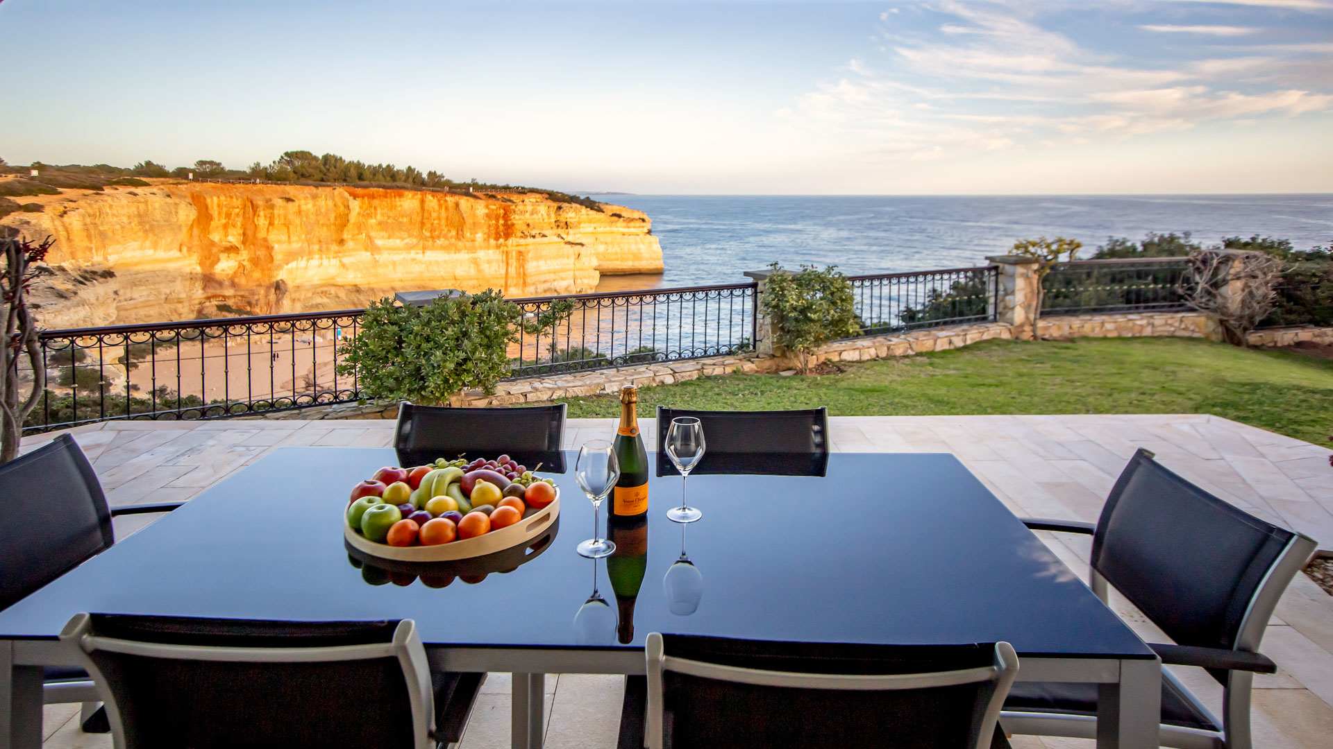 Exclusive Resorts' private villa terrace in Algarve with ocean views and a table set with fruit and champagne.