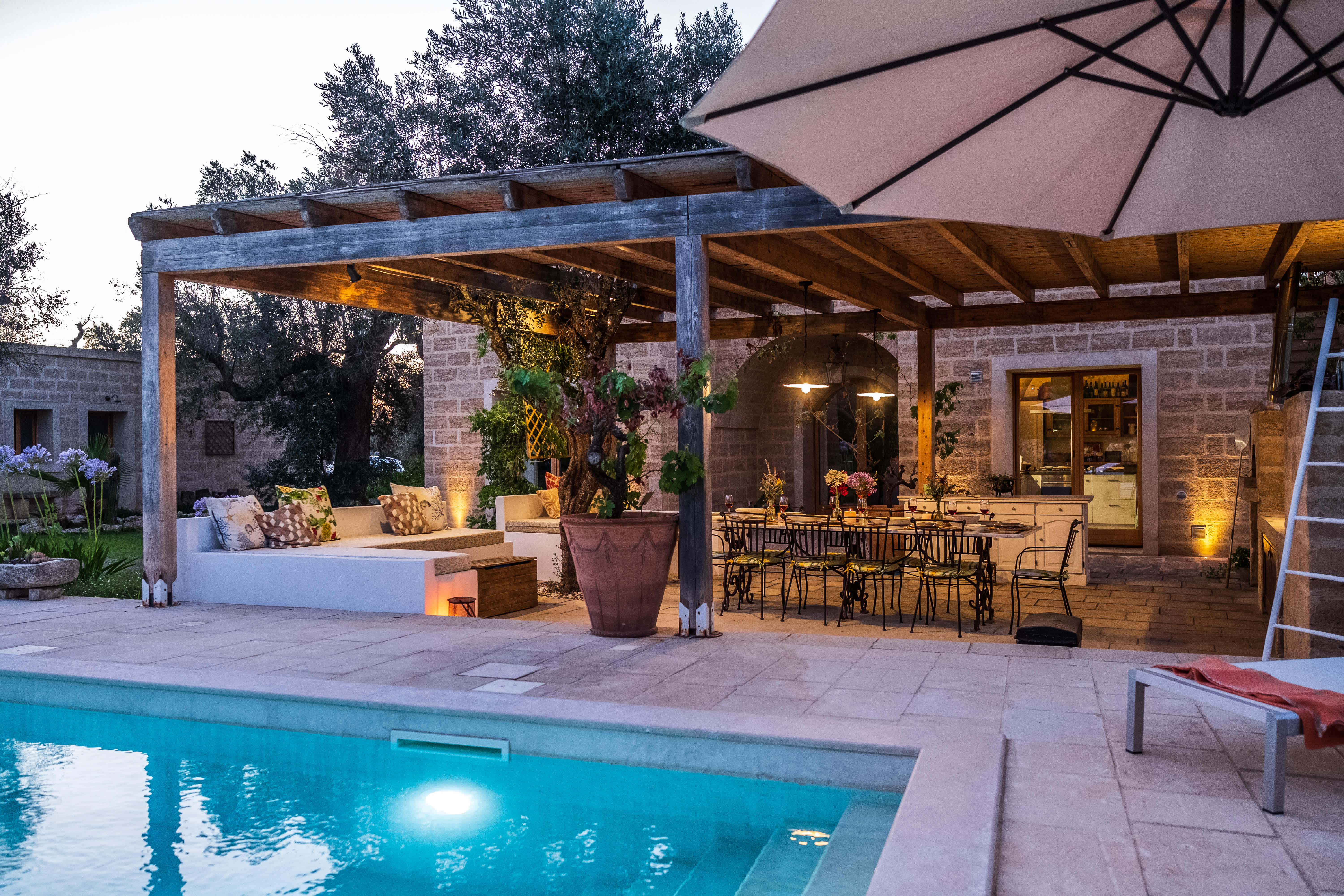 Exclusive Resorts' private villa in Puglia, Italy, with a charming outdoor dining area and poolside seating under a pergola.