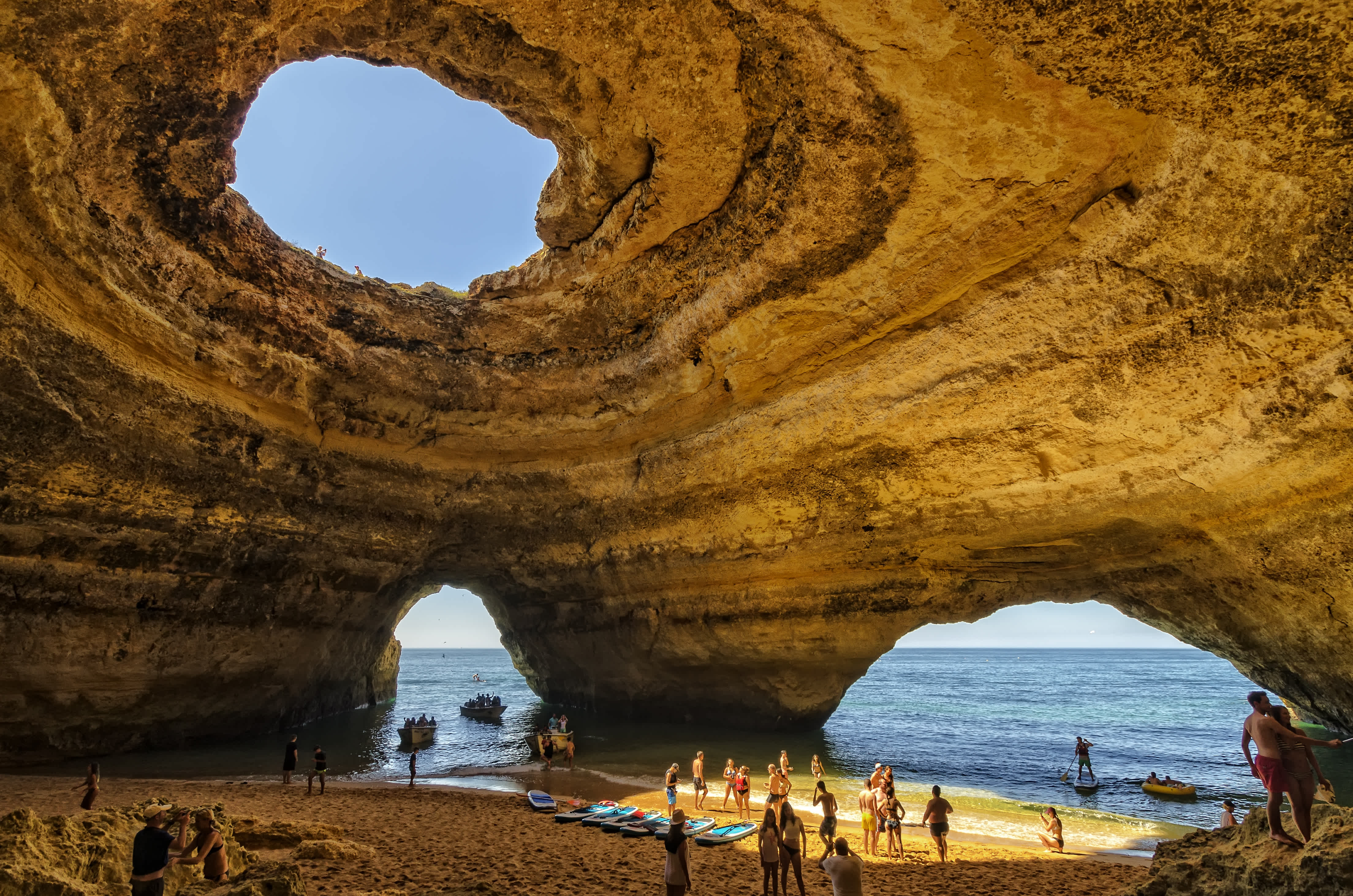 Tourists inside the Benagil Cave with openings to the sky and ocean in Algarve, Portugal.