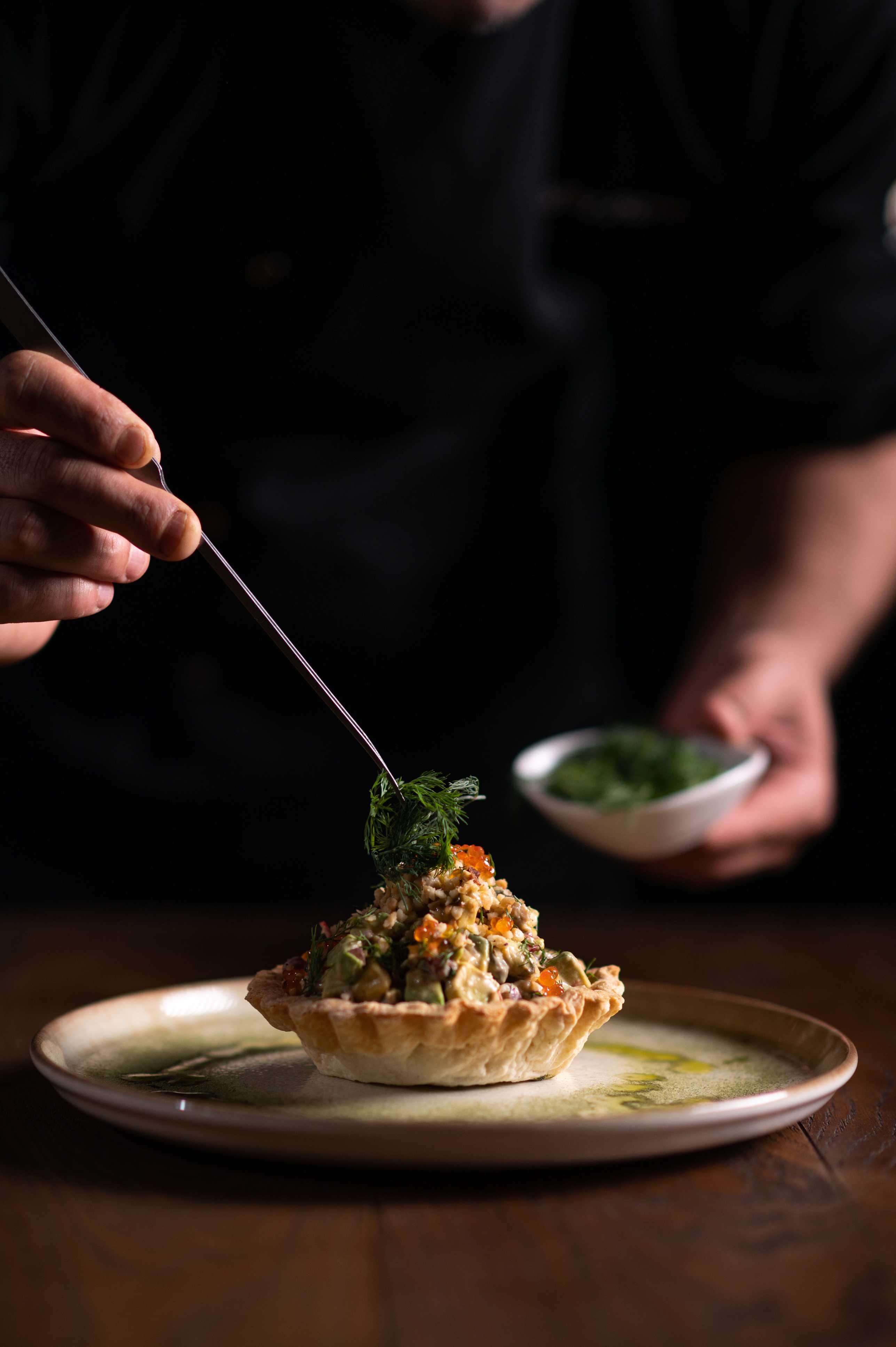 Chef garnishing a gourmet tart with fresh herbs, highlighting the culinary artistry of Provence cuisine.