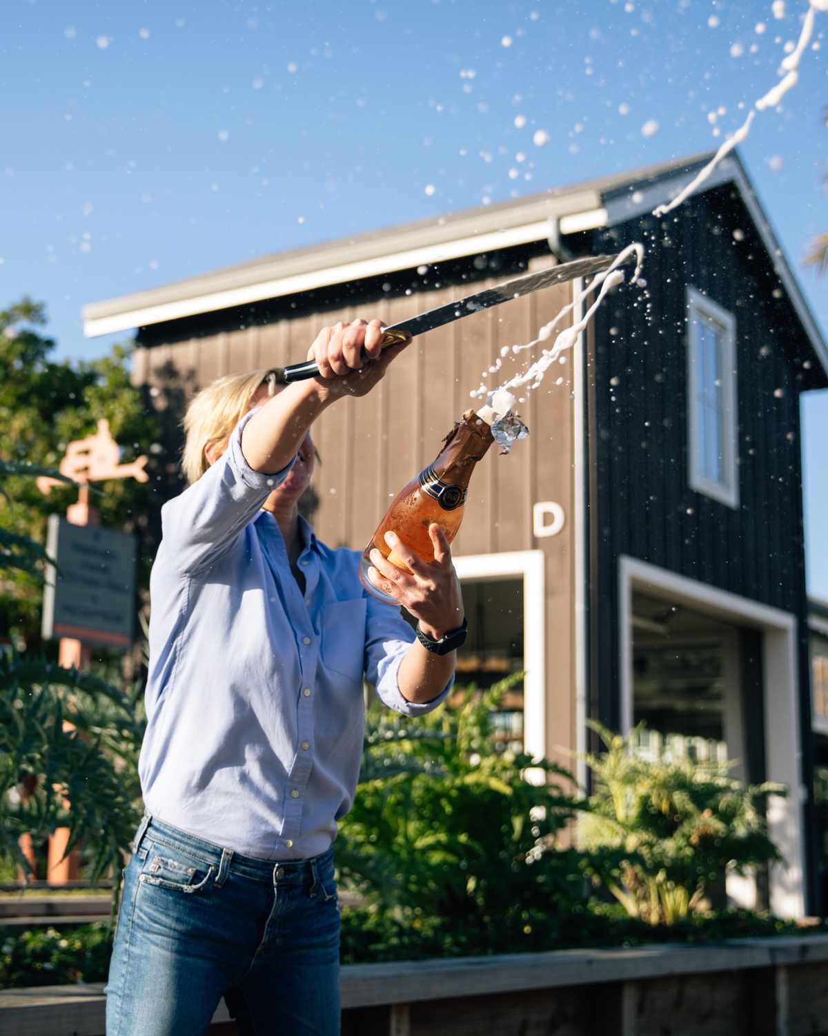 A person opening a champagne bottle with a sword in Napa Valley vineyard.