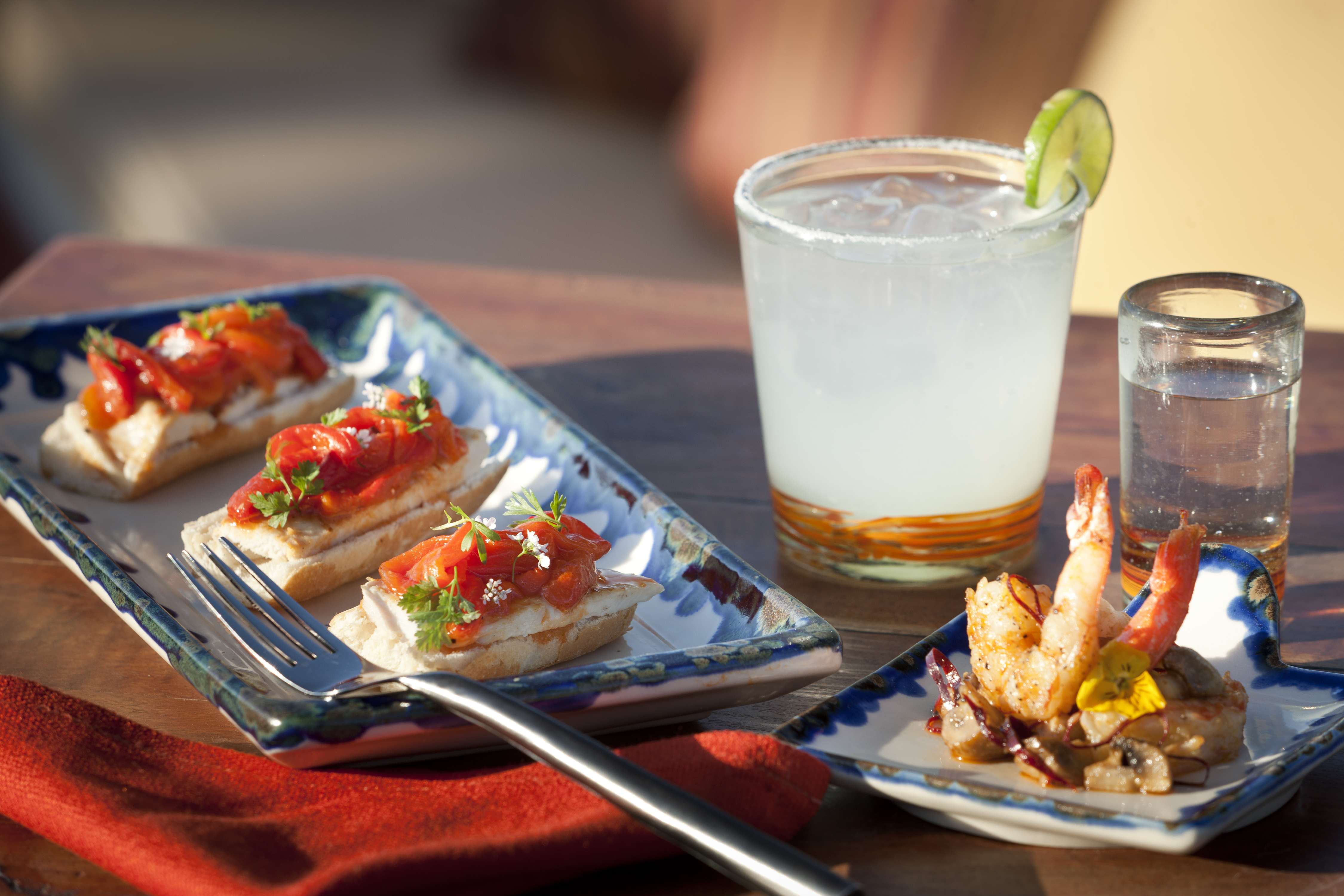 Gourmet appetizers with a cocktail and tequila shot on a table, ready to be enjoyed.