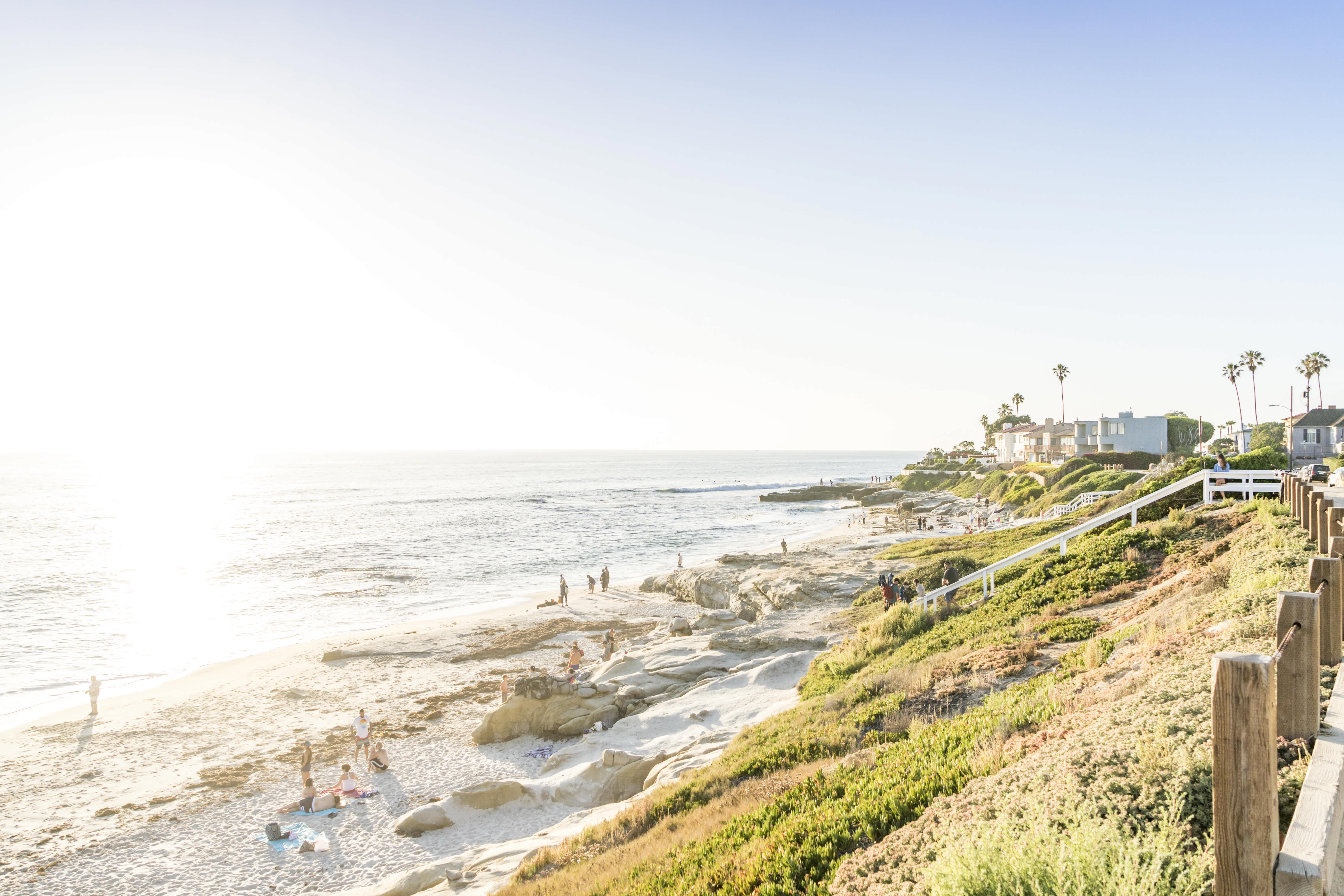 La Jolla coastline during sunset with beachgoers and oceanfront homes.
