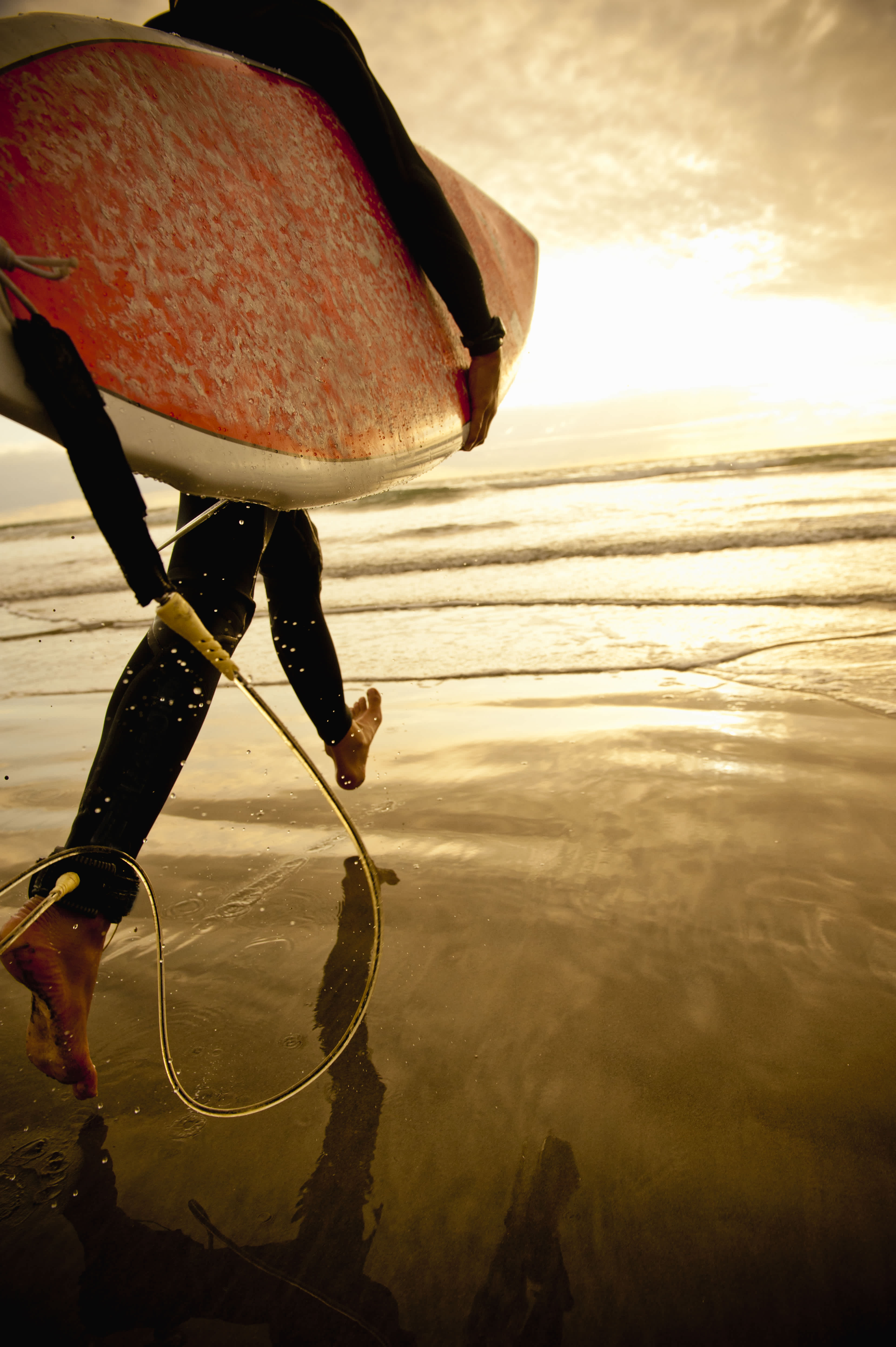 Surfer walking into the water at the beach.