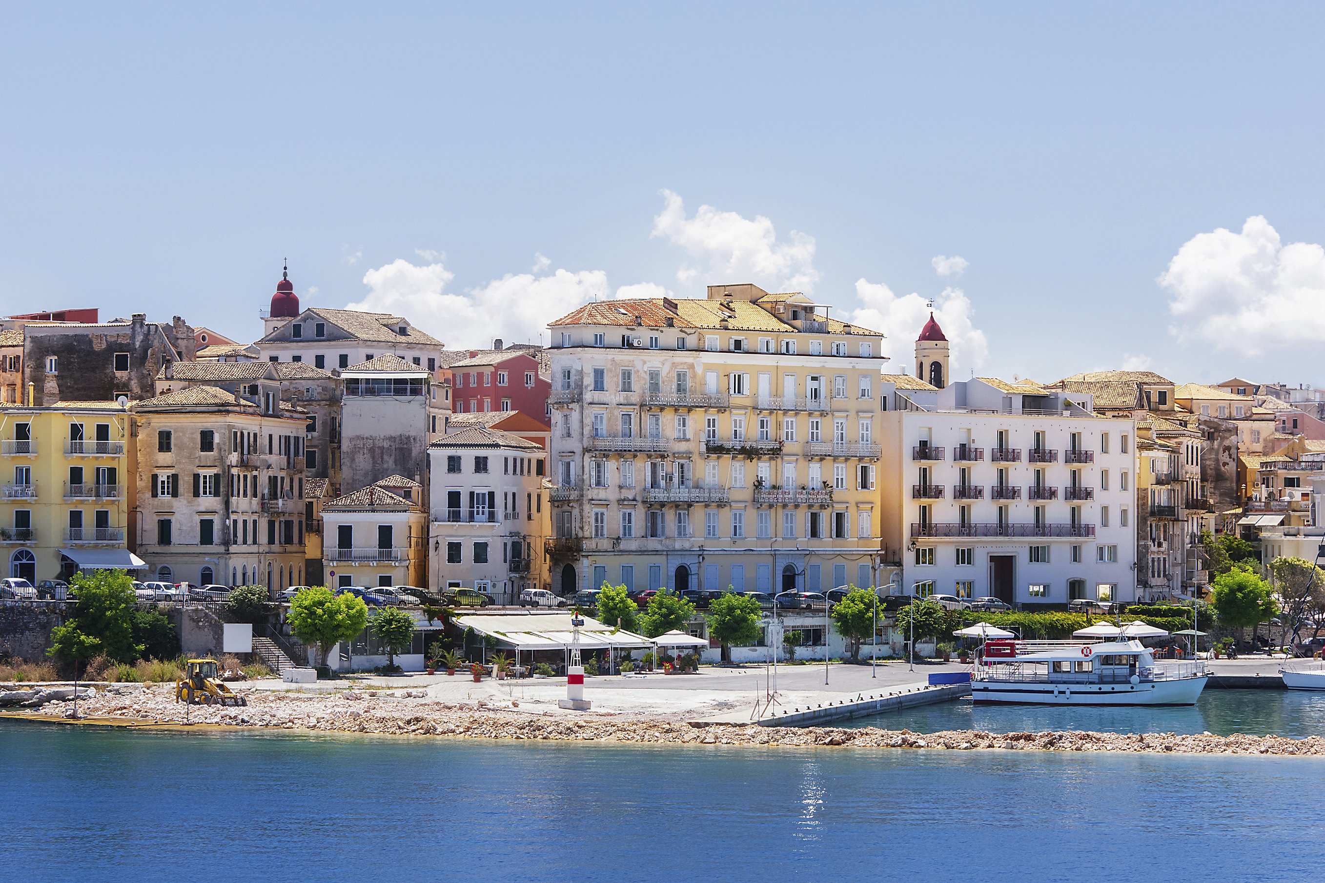 Scenic view of Corfu Town with colorful buildings and boats docked by the waterfront.