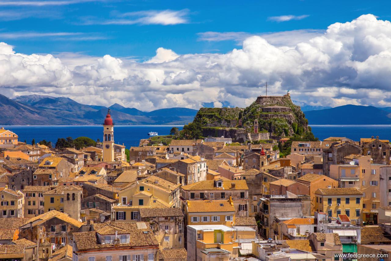 Panoramic view of Corfu Town with the Old Fortress and mountains in the background.