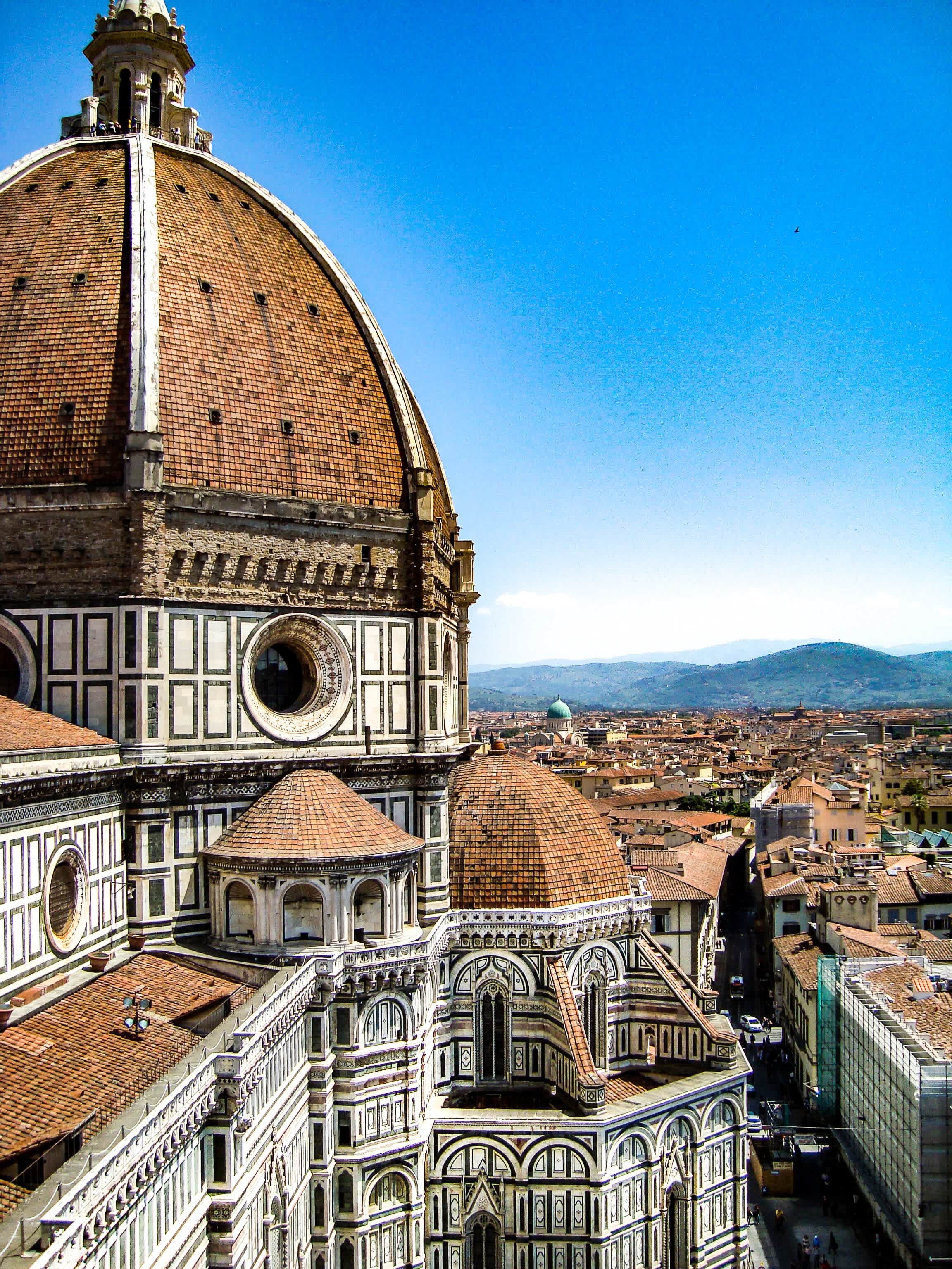 View of the Florence Cathedral dome with cityscape and mountains in the background