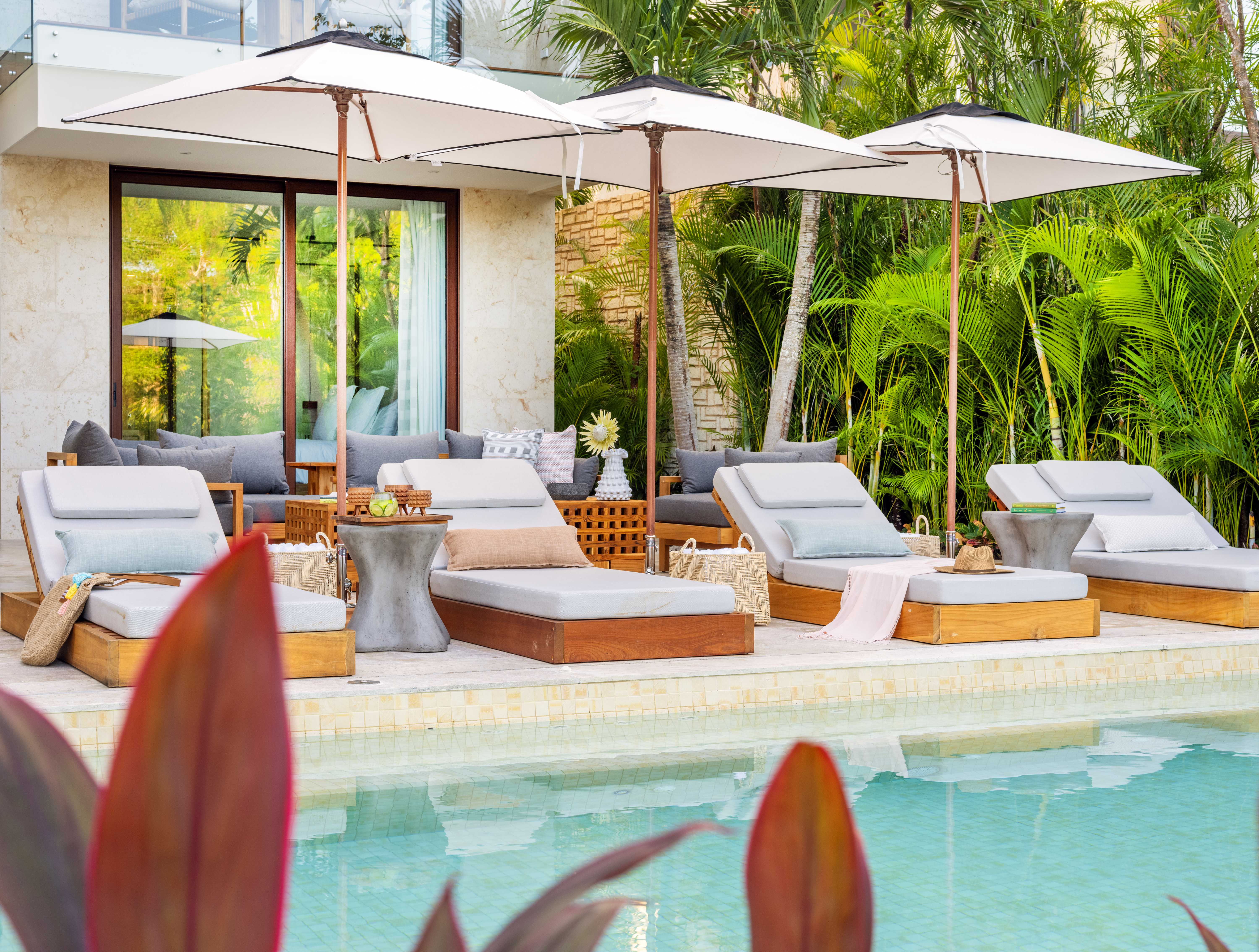 Poolside lounge area at Rosewood Mayakoba with sun loungers, umbrellas, and lush greenery.