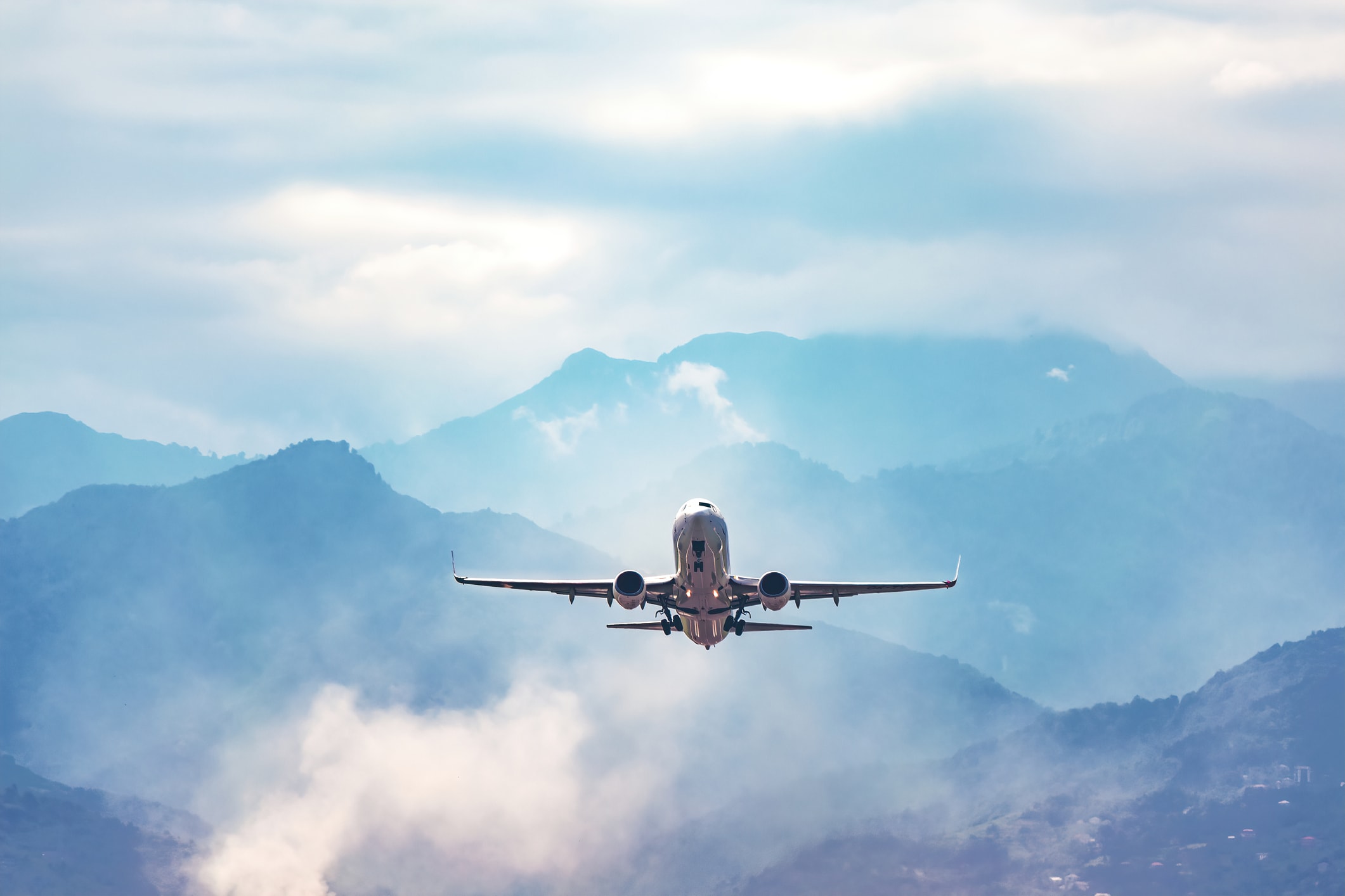 A private jet taking off with mountains in the background.