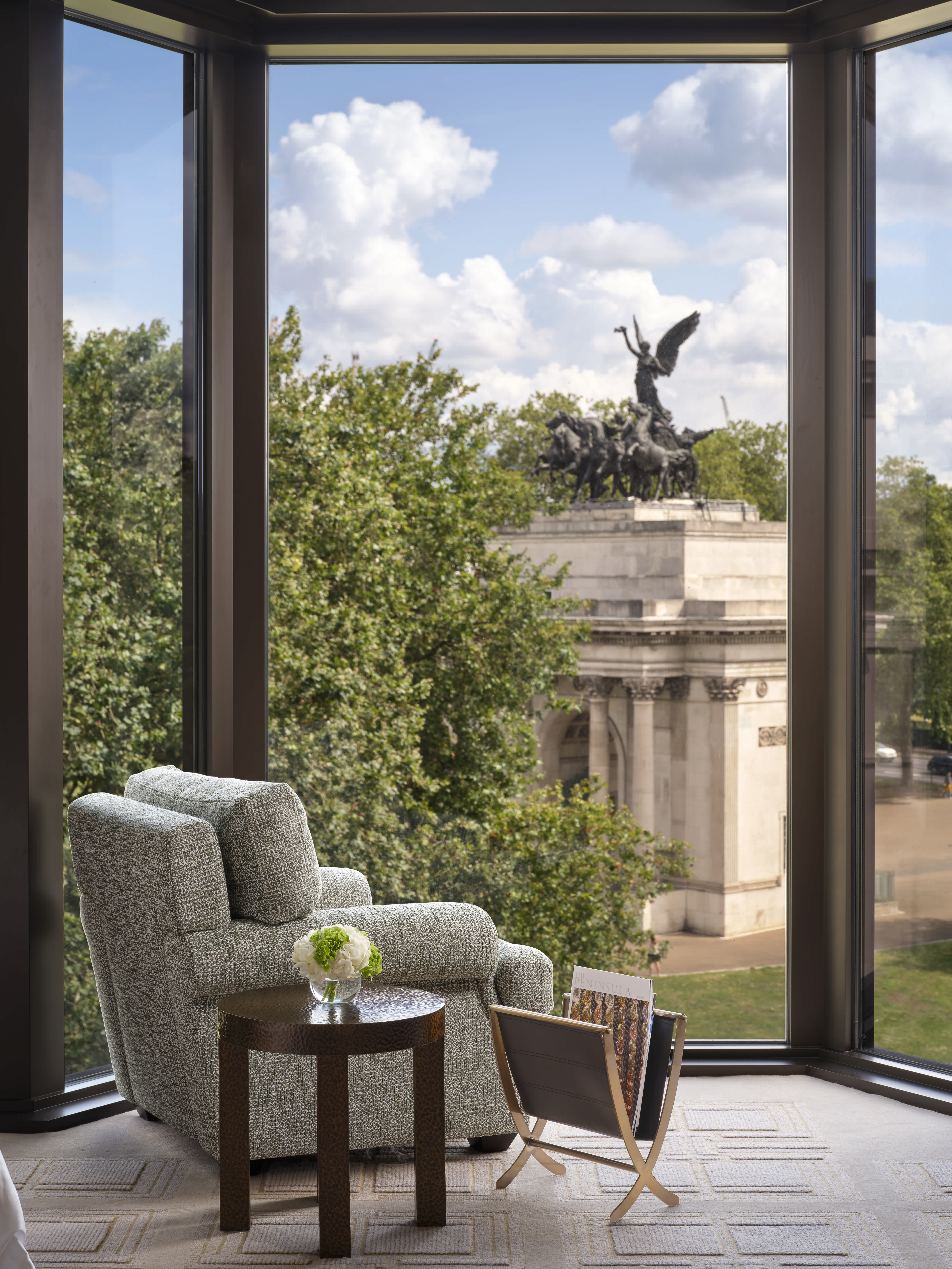 A cozy seating area with a large window offering a view of the iconic Wellington Arch from an Exclusive Resorts suite at The Peninsula London.