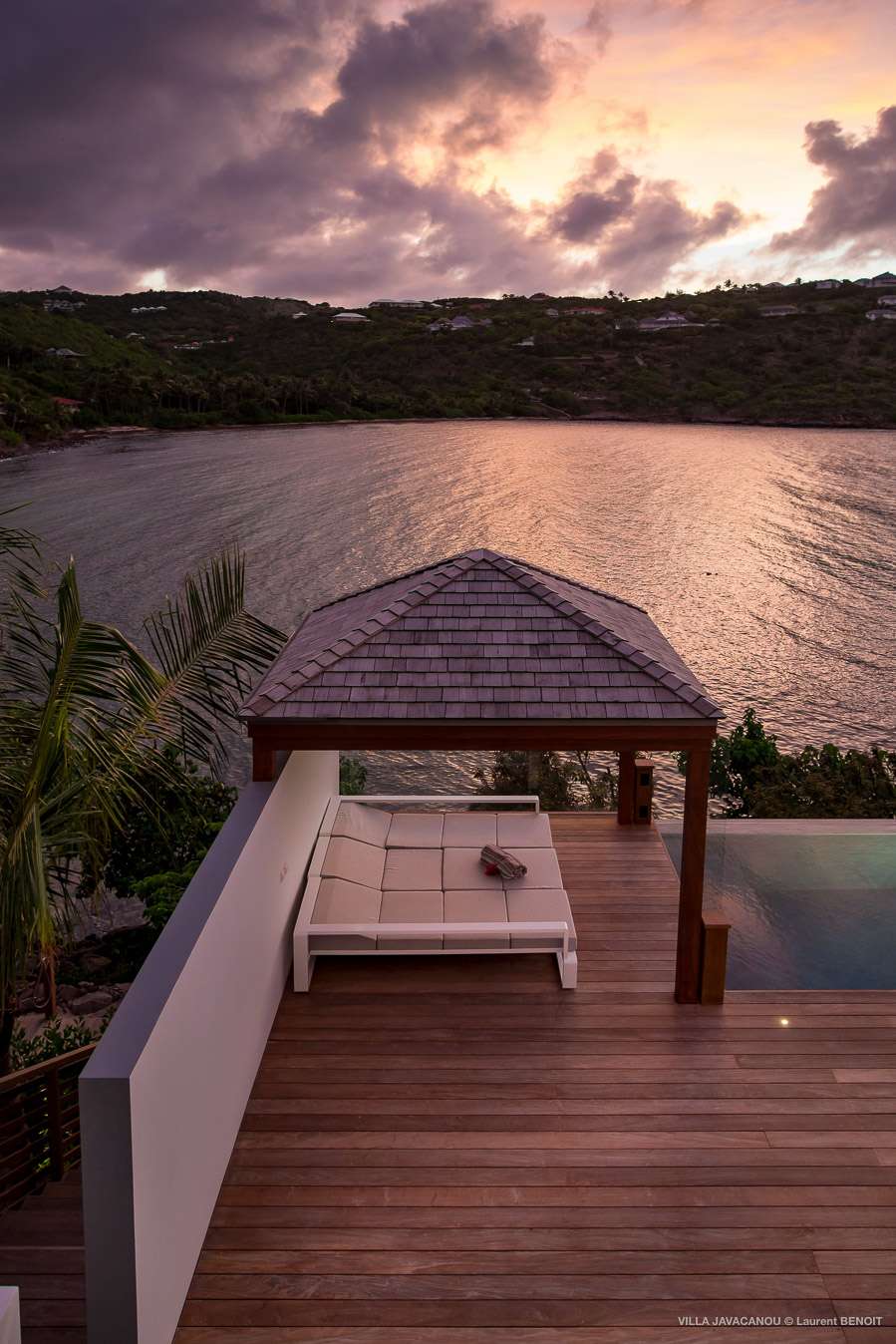 Sunset view from Exclusive Resorts' villa in St. Barts, featuring a private deck with a gazebo overlooking the calm waters.