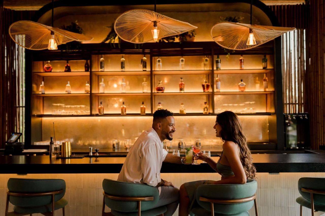 Couple enjoying drinks at the bar in Ostra restaurant, Costa Rica, with a warm and intimate atmosphere.