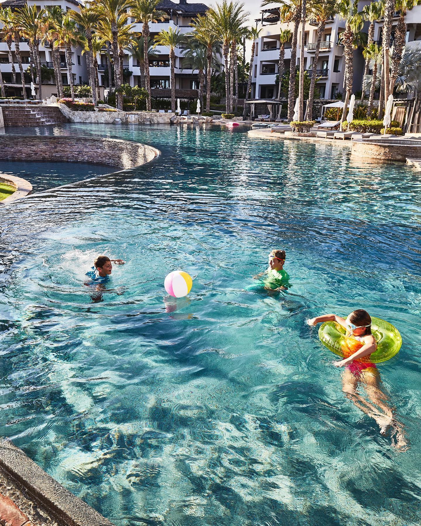 Three kids playing with a beach ball at an Exclusive Resort's property in Los Cabos, Mexico.