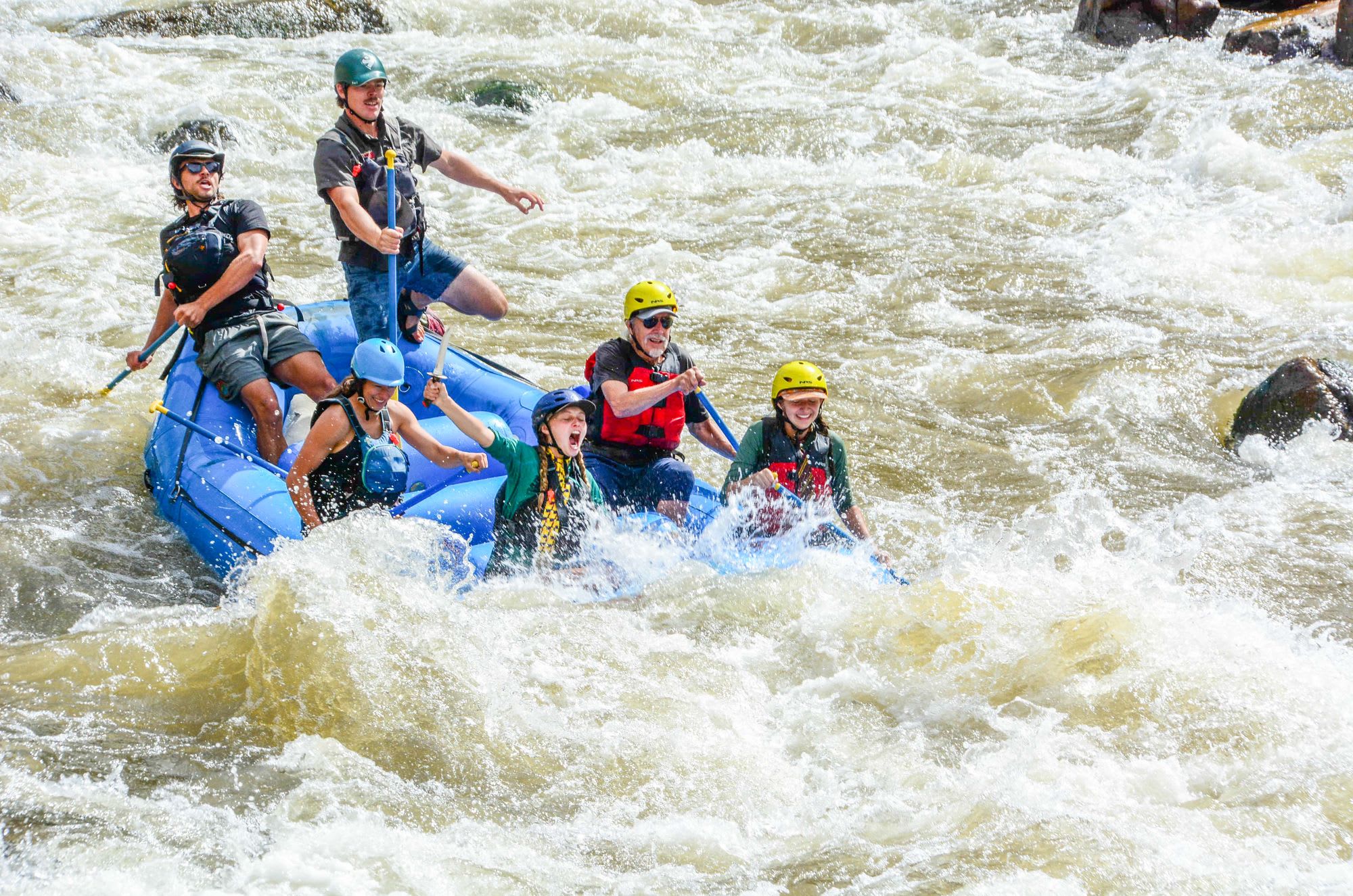Group of people white-water rafting through rapids in a river in Colorado.