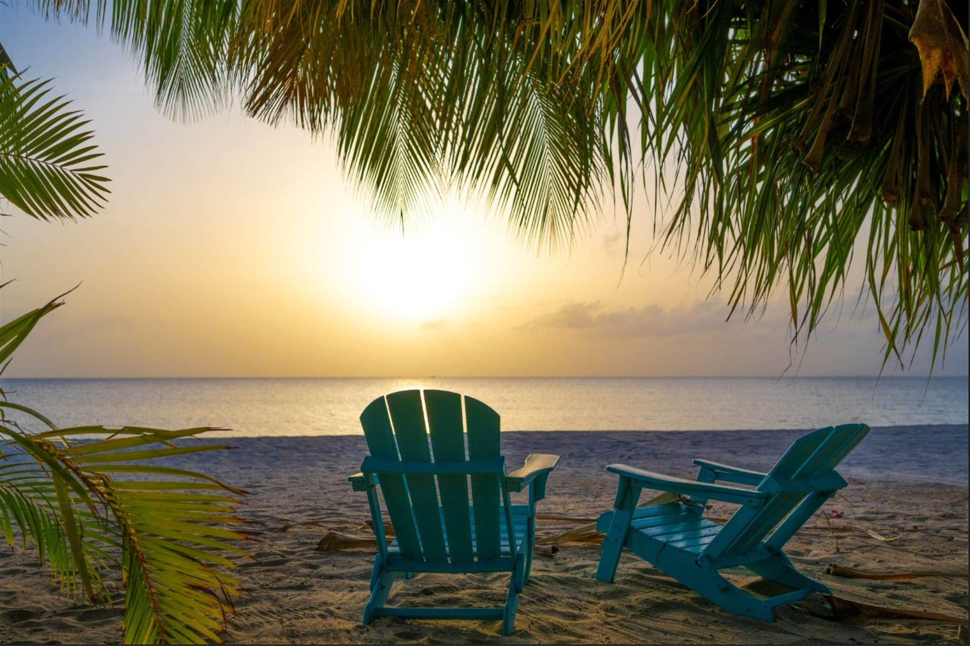 Sunrise view from Paradise Beach in Nevis with empty lounge chairs on the sand