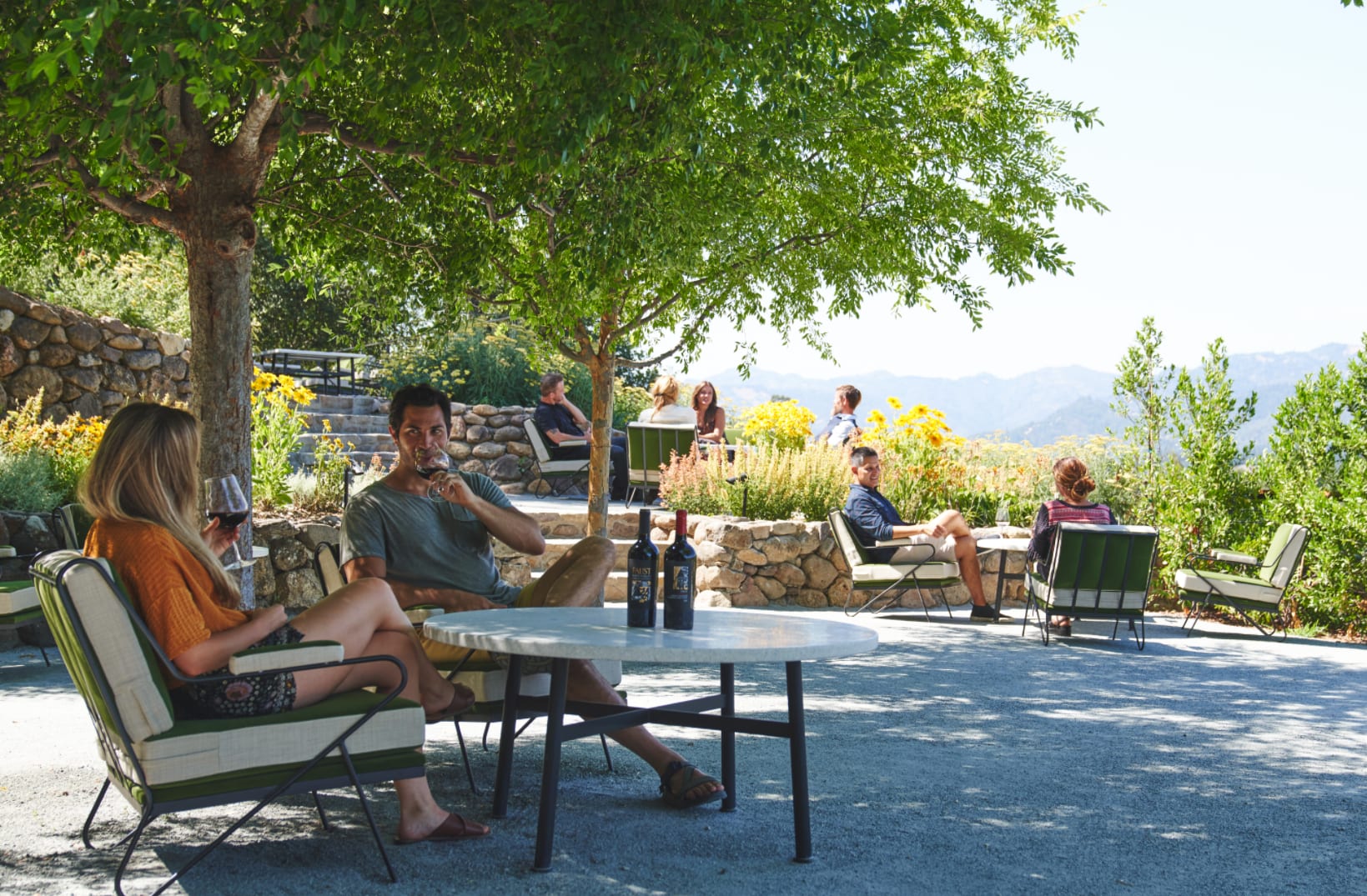 People enjoying wine at an outdoor seating area at Faust Winery in Napa Valley with scenic views