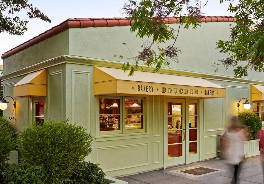 Exterior of Bouchon Bakery in Napa Valley with yellow awnings and greenery