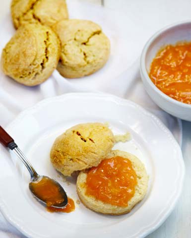Freshly baked scones with apricot jam served on a white plate