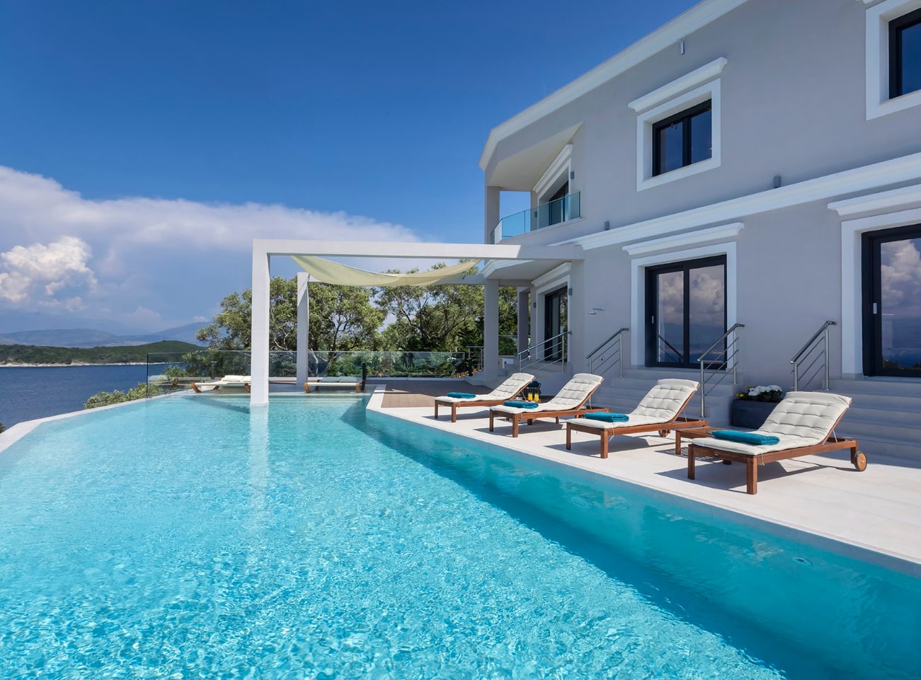 Exclusive Resorts' luxury villa in Corfu, Greece, featuring an infinity pool with ocean views and sun loungers.