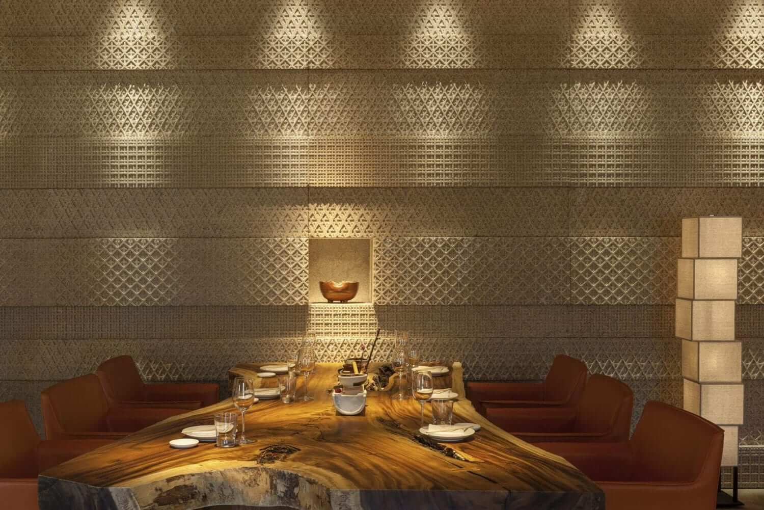 Elegant restaurant interior in Rome with a large wooden table, set for dining, and intricate wall design.
