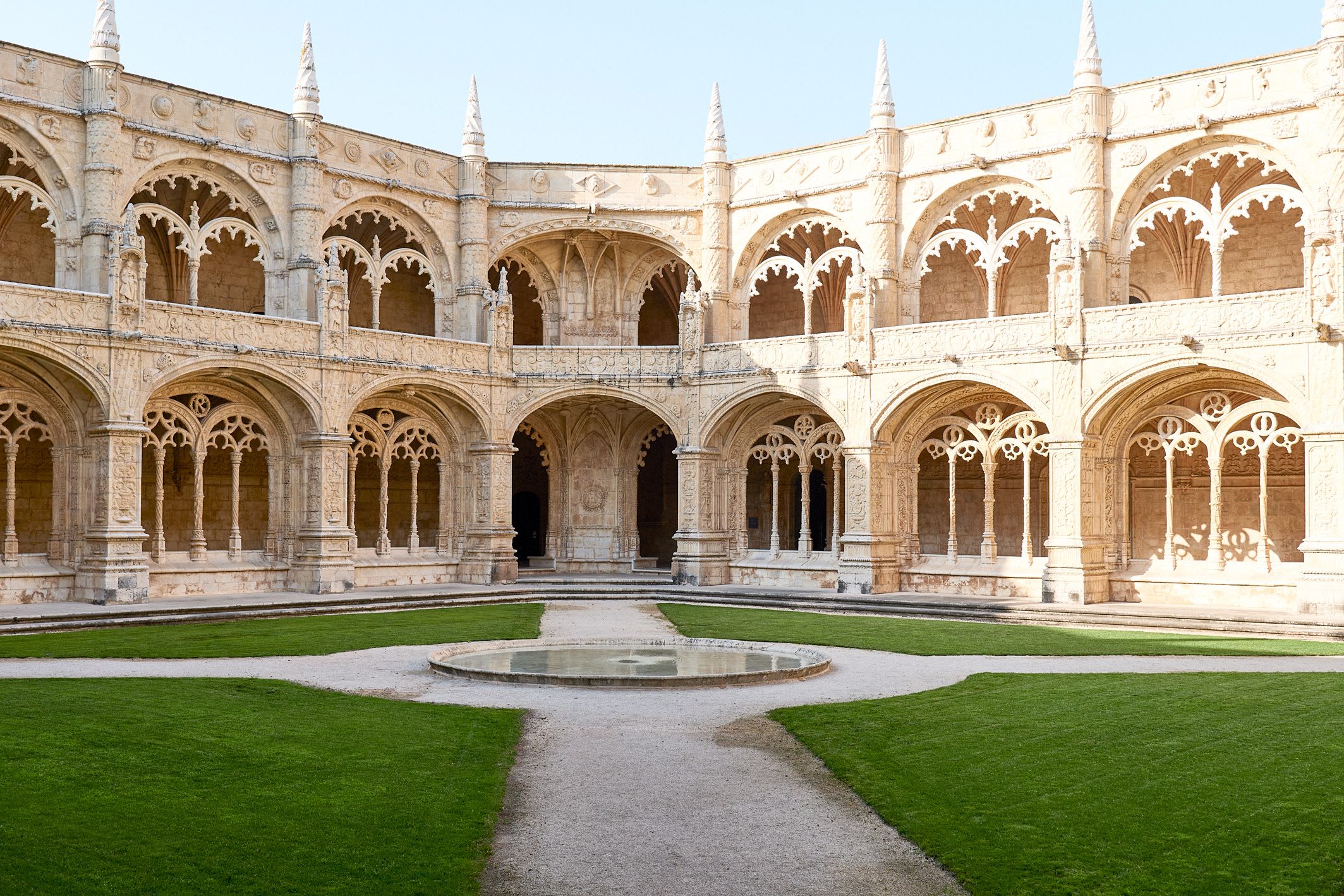 Central courtyard with green grass and historic arched walkways at Jerónimos Monastery in Lisbon, Portugal