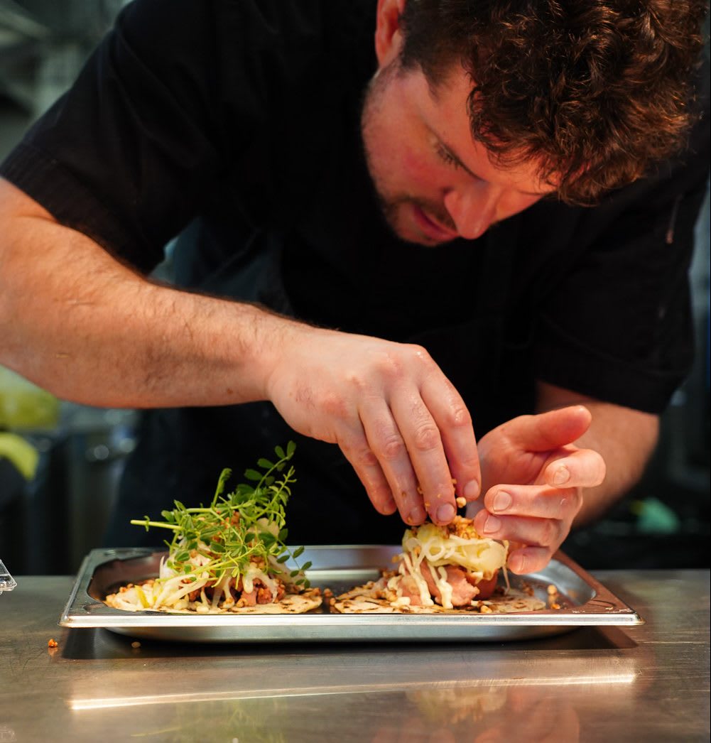 Chef carefully preparing a dish on a tray at Výčep in Prague
