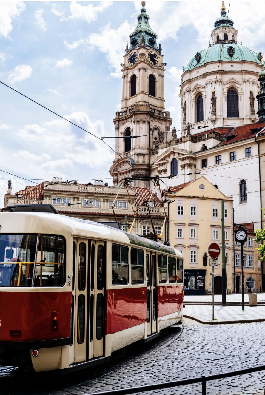 Historic tram in front of St. Nicholas Church with towers and a domed roof in Prague, Czech Republic