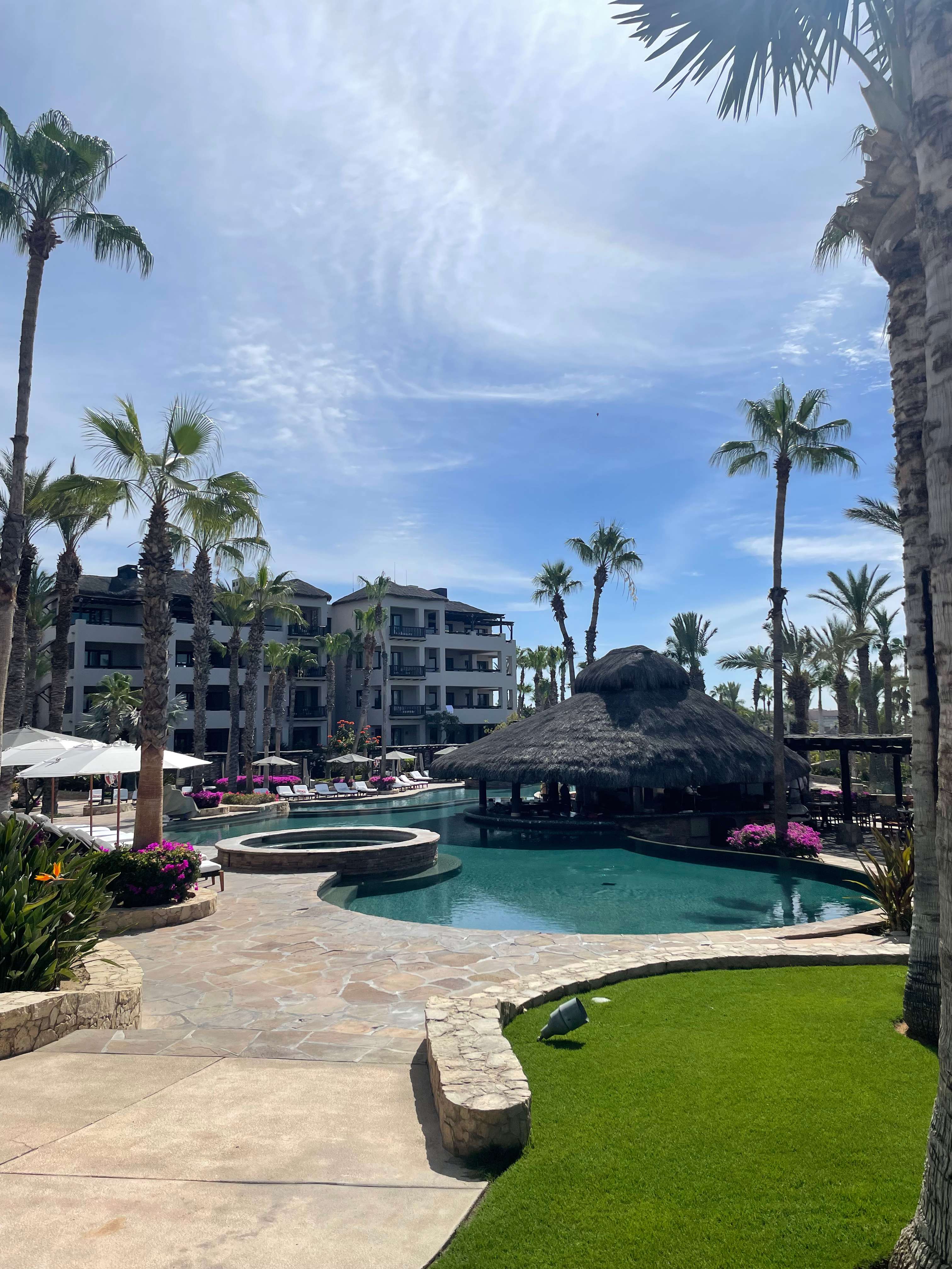 View of the pool area at Esperanza in Los Cabos, Mexico, surrounded by palm trees and resort buildings.