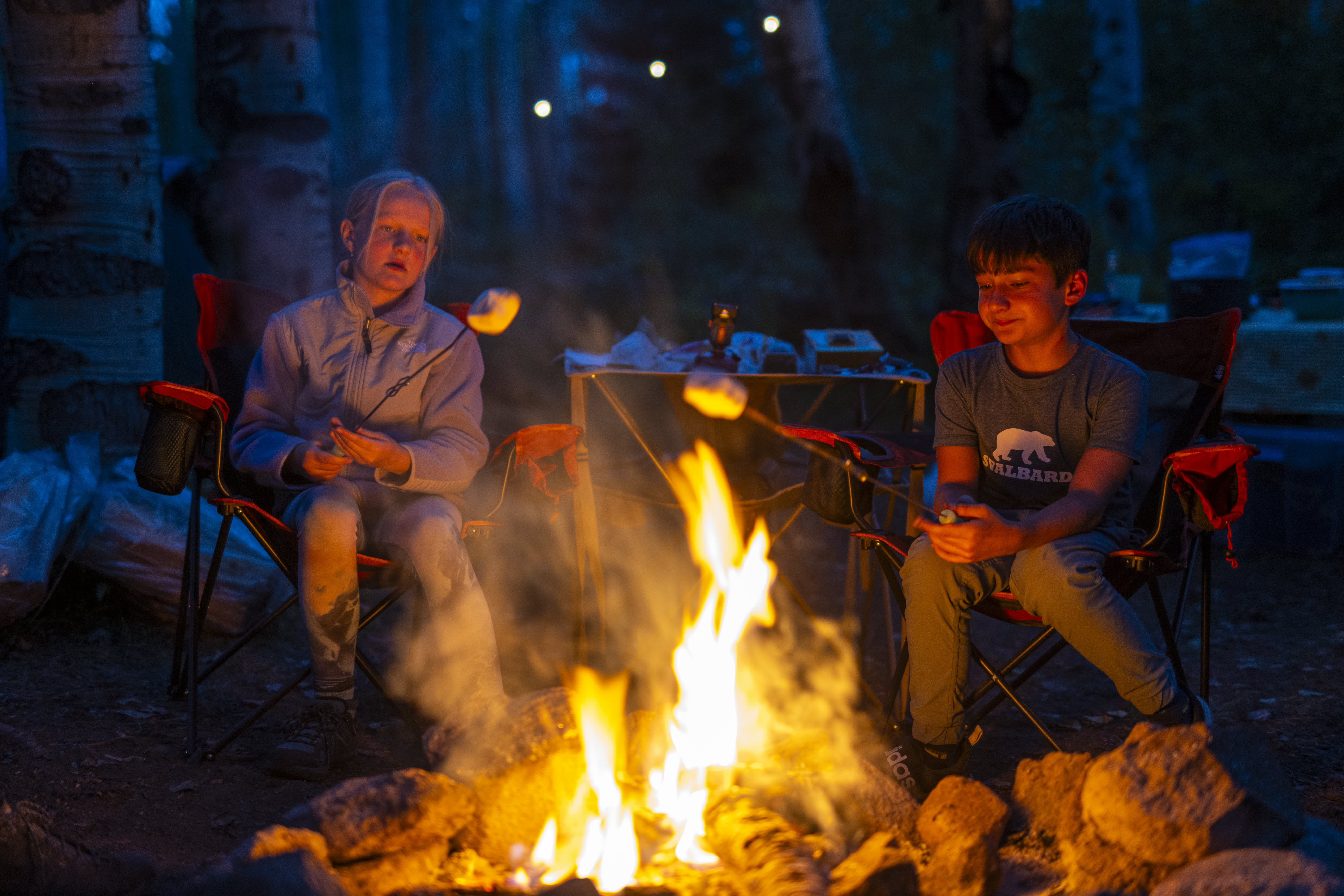 A child roasting marshmallows by a campfire during an evening camping trip in Colorado.