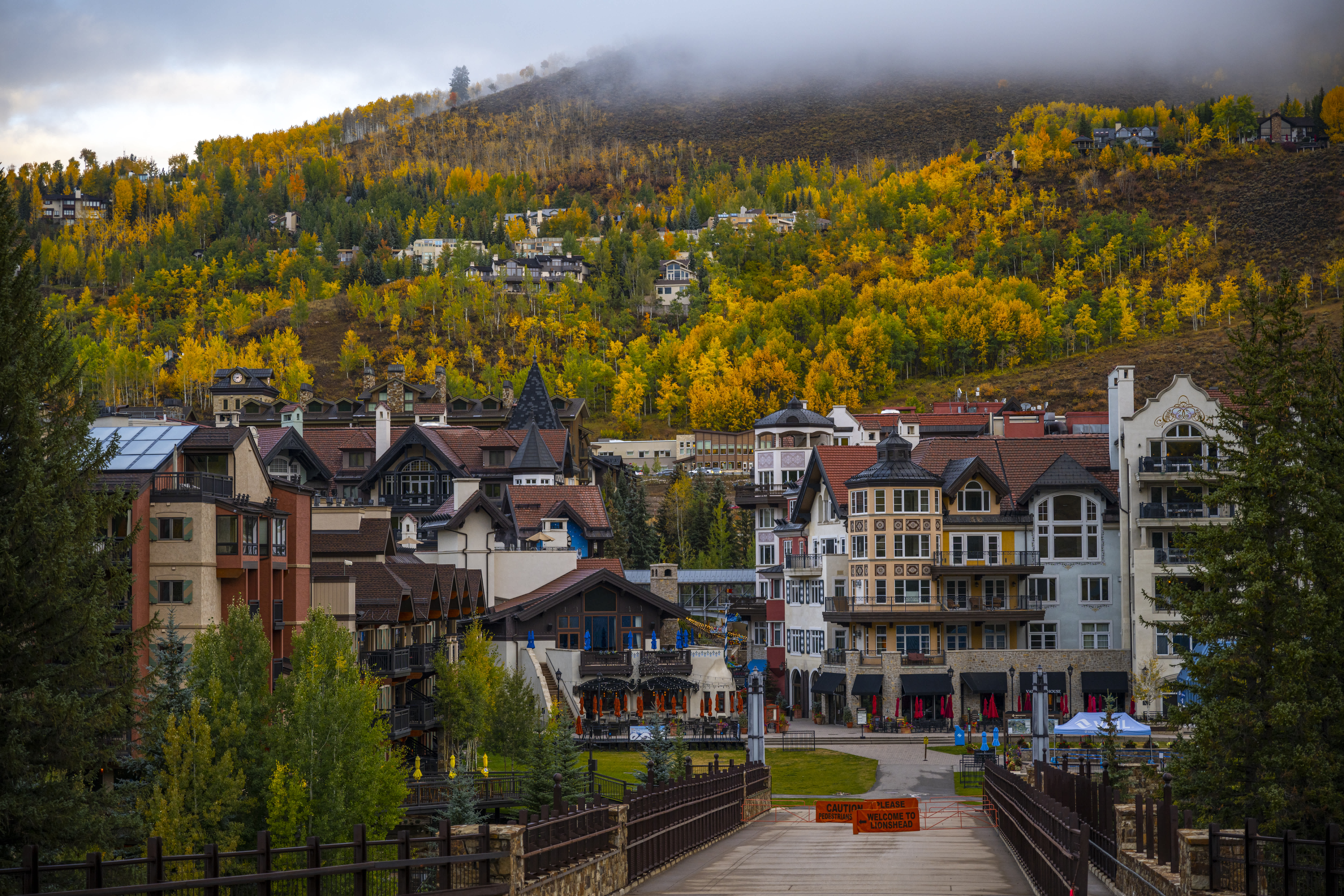 A picturesque mountain village in Colorado with autumn foliage on the surrounding hillsides, partially covered by mist.
