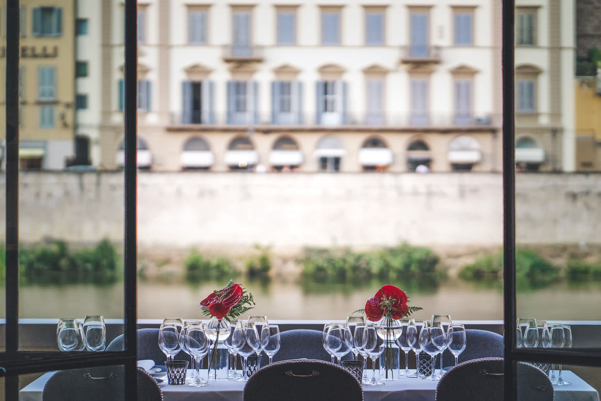 Elegant dining terrace with set tables overlooking a historic building at Borgo San Jacopo in Florence, Italy