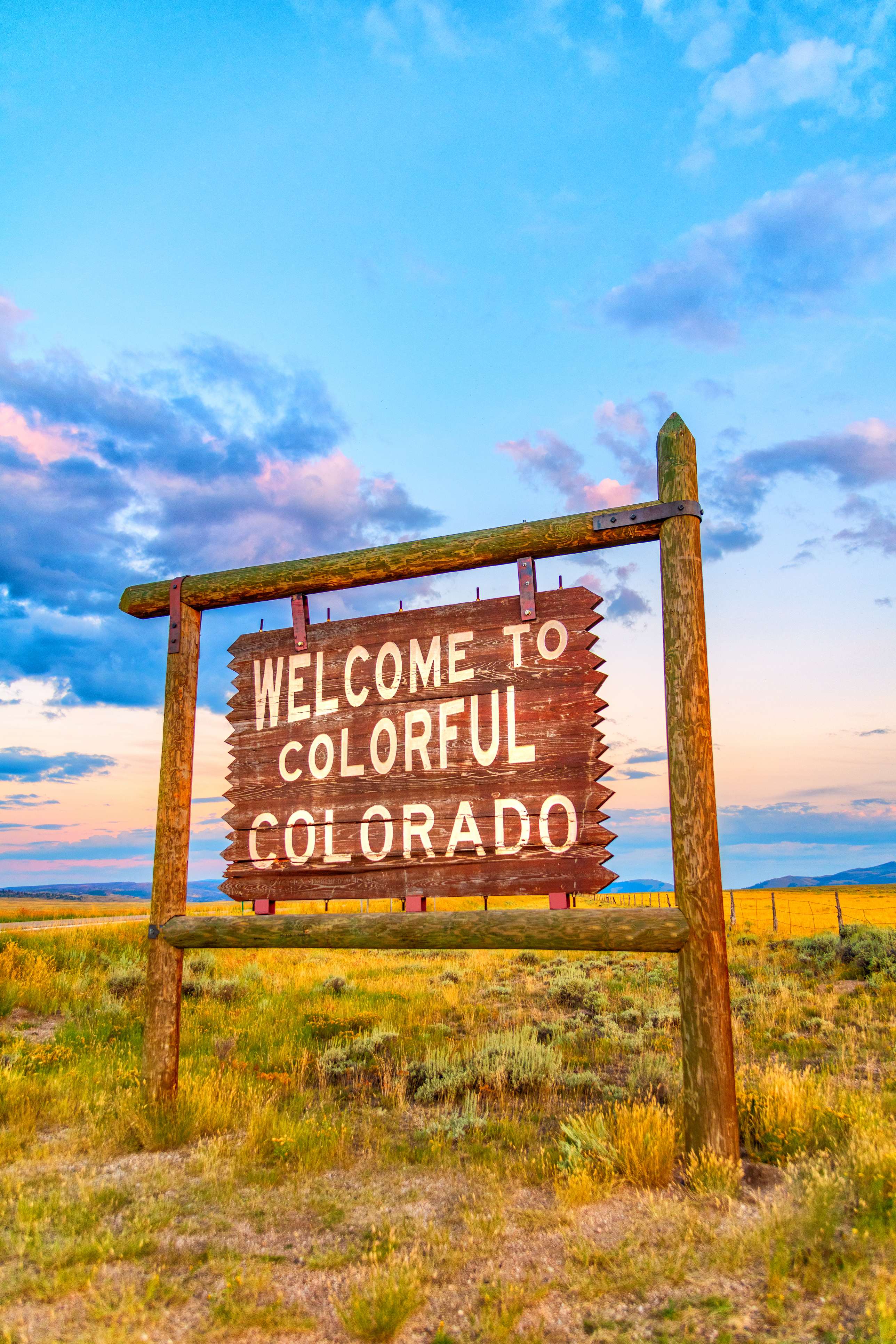 The "Welcome to Colorful Colorado" sign at sunset along a scenic road trip.
