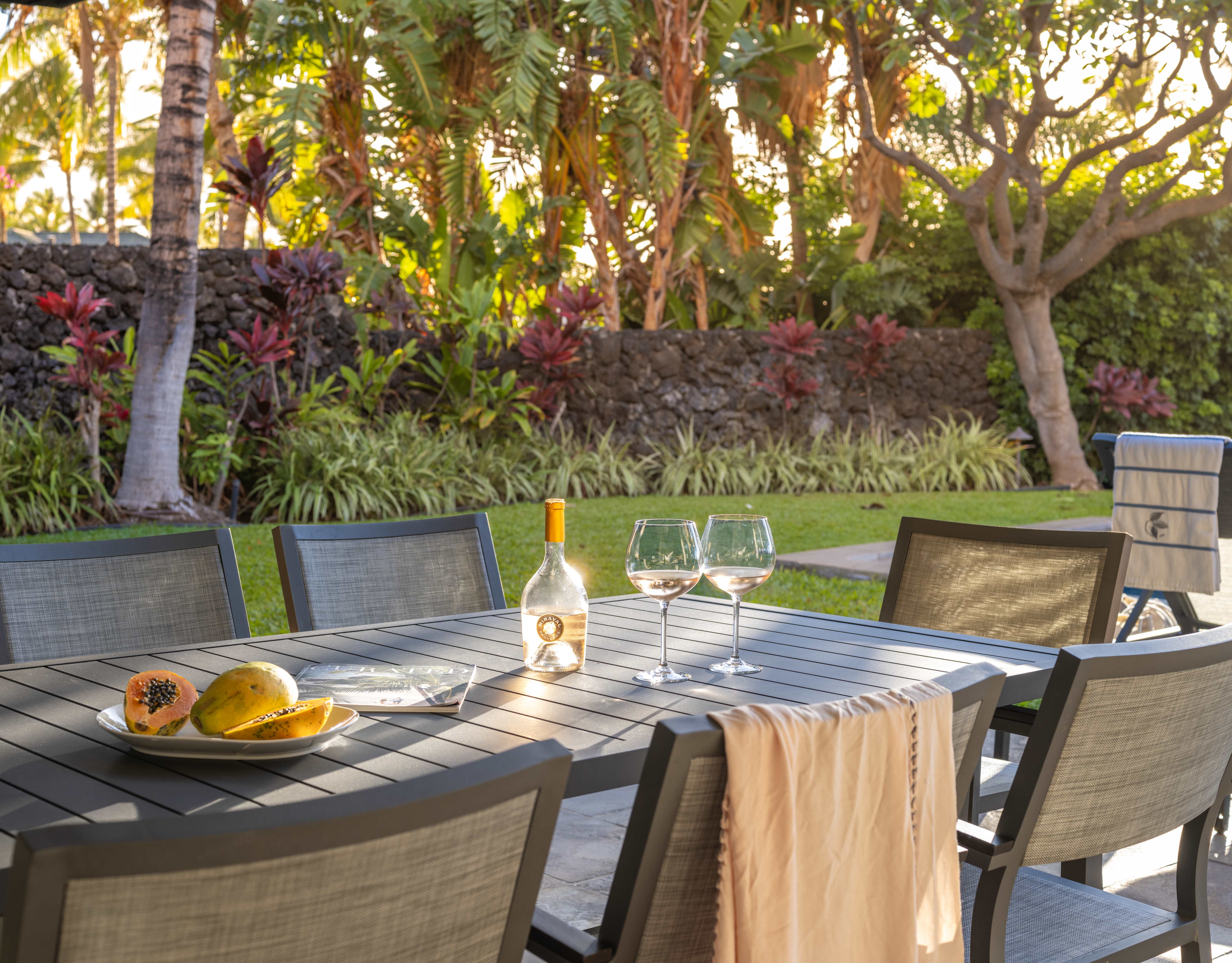 Outdoor dining table with wine and tropical fruits at Pauoa Beach Club on the Kohala Coast.