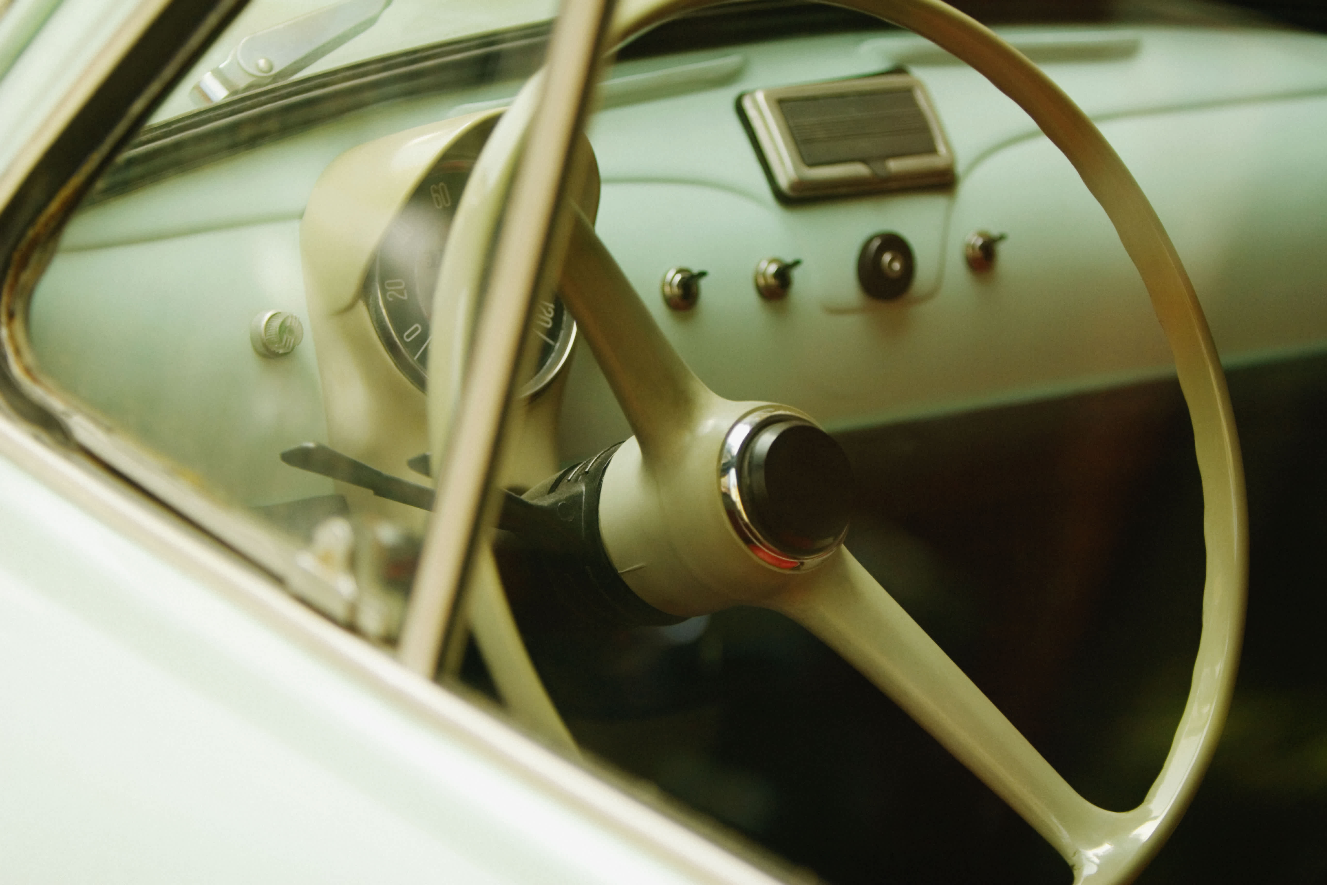 Close-up of a vintage car steering wheel and dashboard.