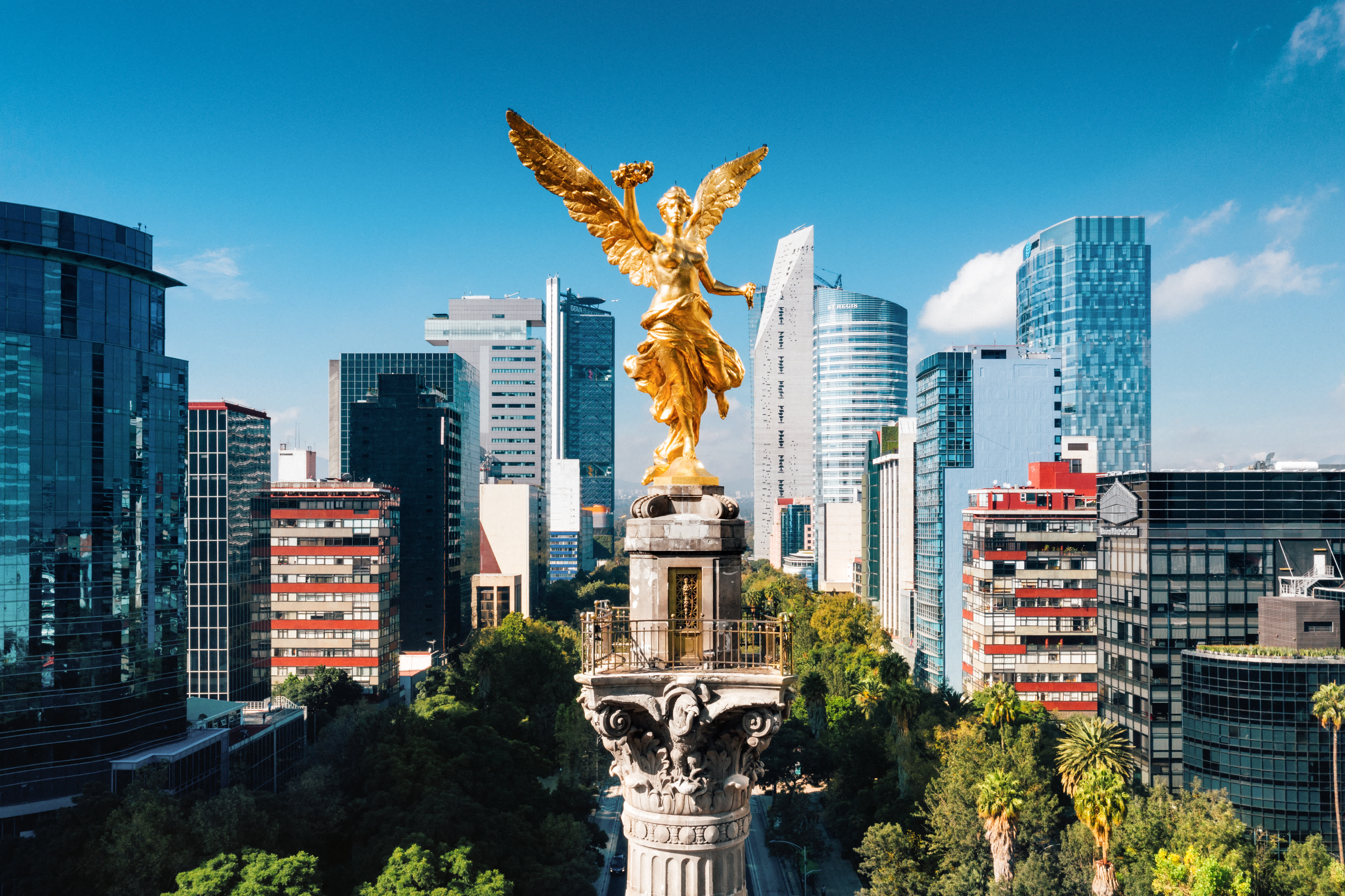 The Angel of Independence monument in Mexico City with modern skyscrapers in the background.