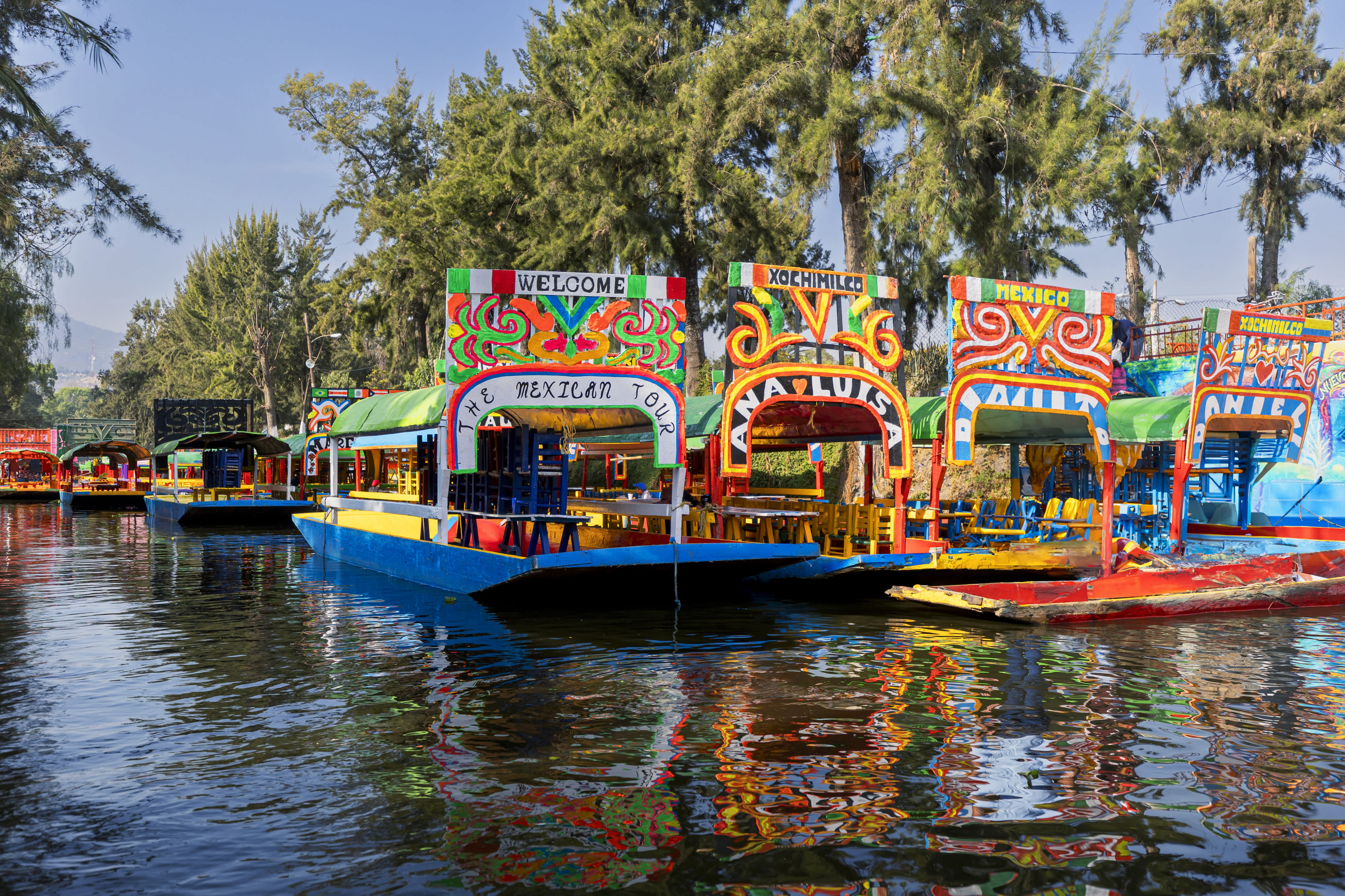 Colorful trajineras (boats) lined up on the water in Xochimilco, Mexico.
