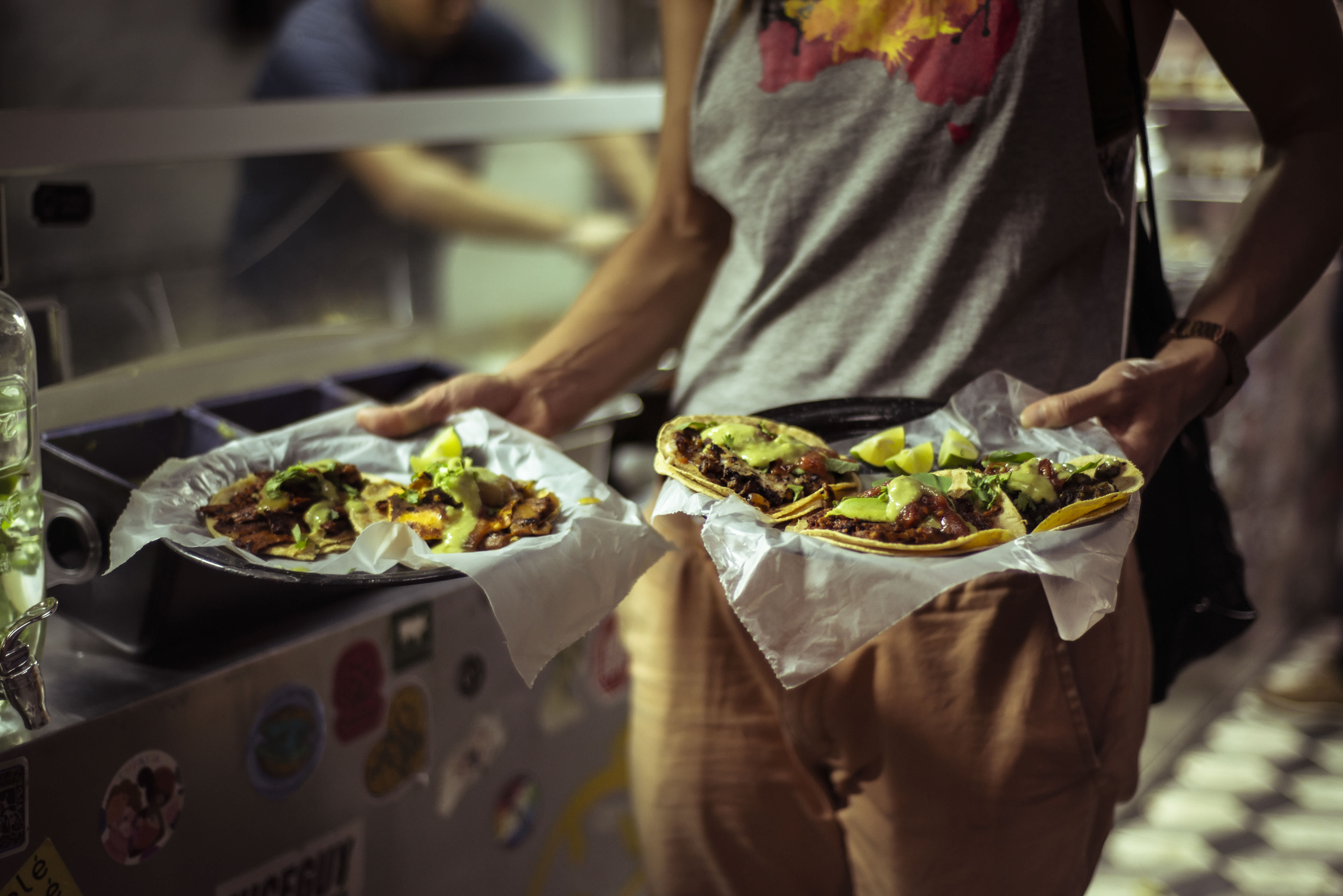Person holding plates of freshly made tacos from a street food stand in Mexico.