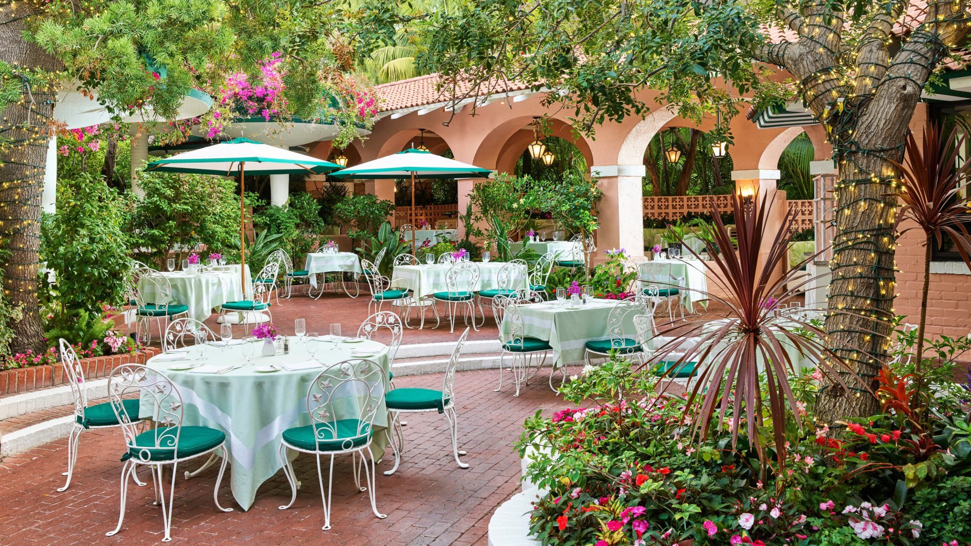 Charming outdoor dining area surrounded by lush greenery at The Peninsula Beverly Hills.