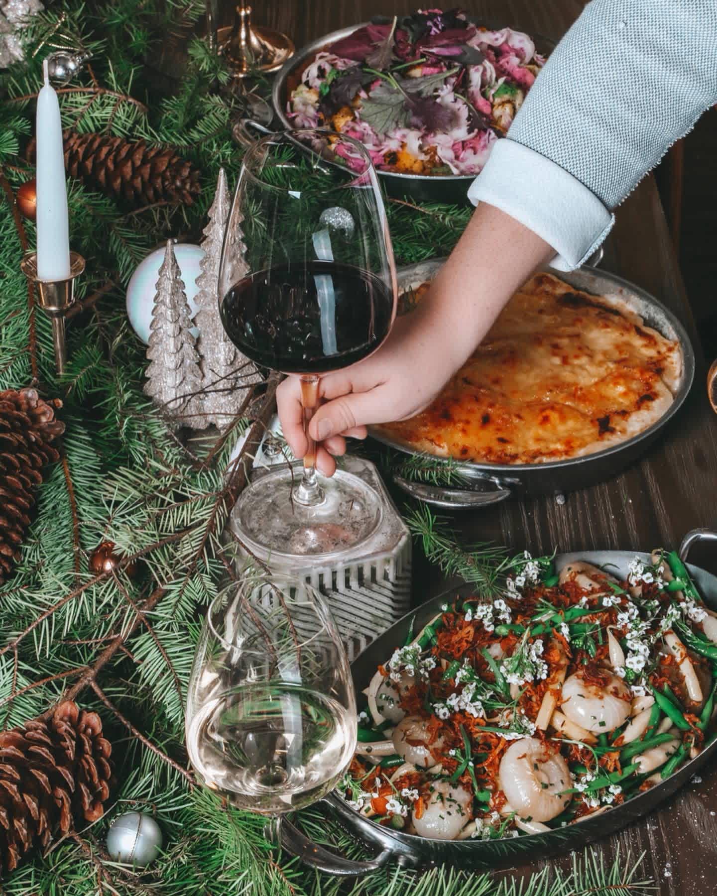 Festive holiday table setting with gourmet dishes and wine being served.