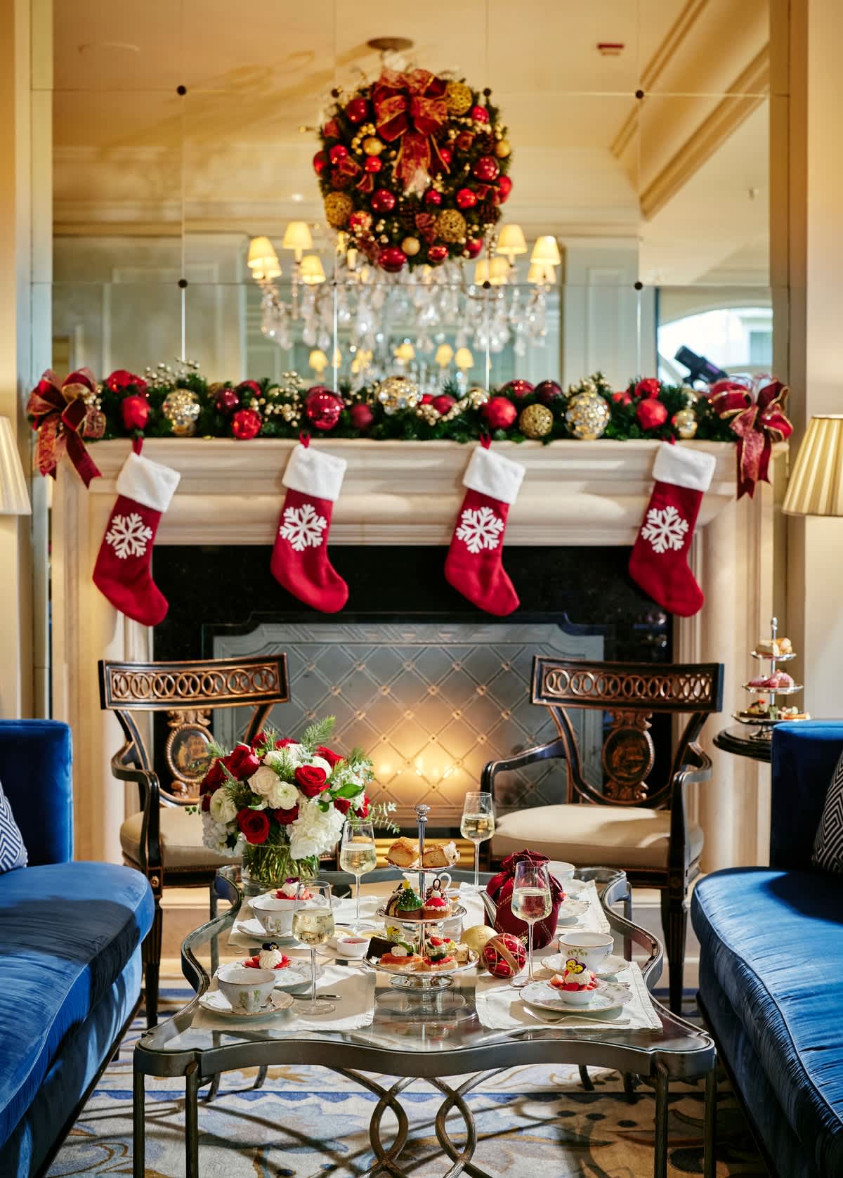 Cozy Christmas-themed afternoon tea setup by a decorated fireplace at The Peninsula Beverly Hills.