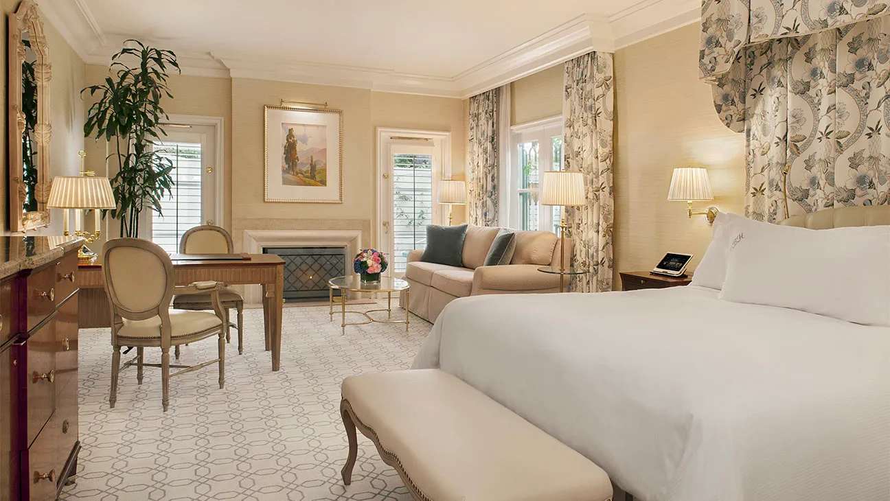 Spacious and elegant bedroom suite at The Peninsula Beverly Hills with a sitting area and fireplace.