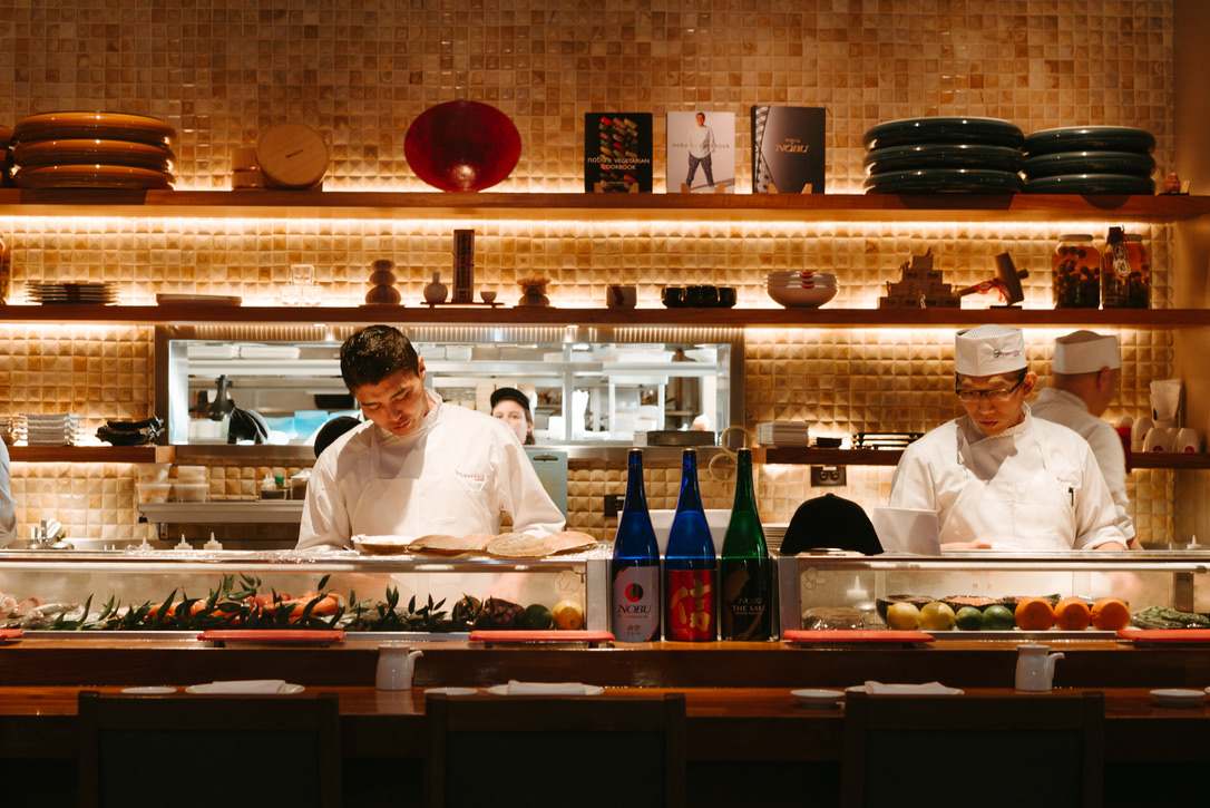 Chefs preparing dishes behind the sushi bar at Matsuhisa, a renowned restaurant known for its Japanese cuisine.