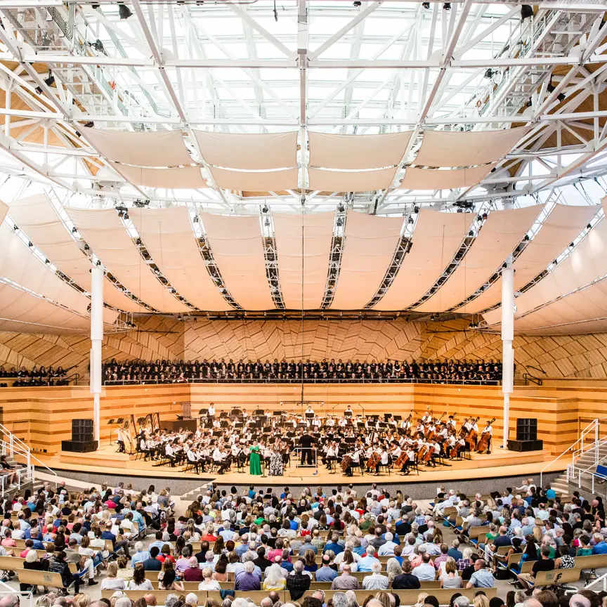 A symphony orchestra performance at the Aspen Music Festival inside a modern, open-air concert hall in Aspen, Colorado.